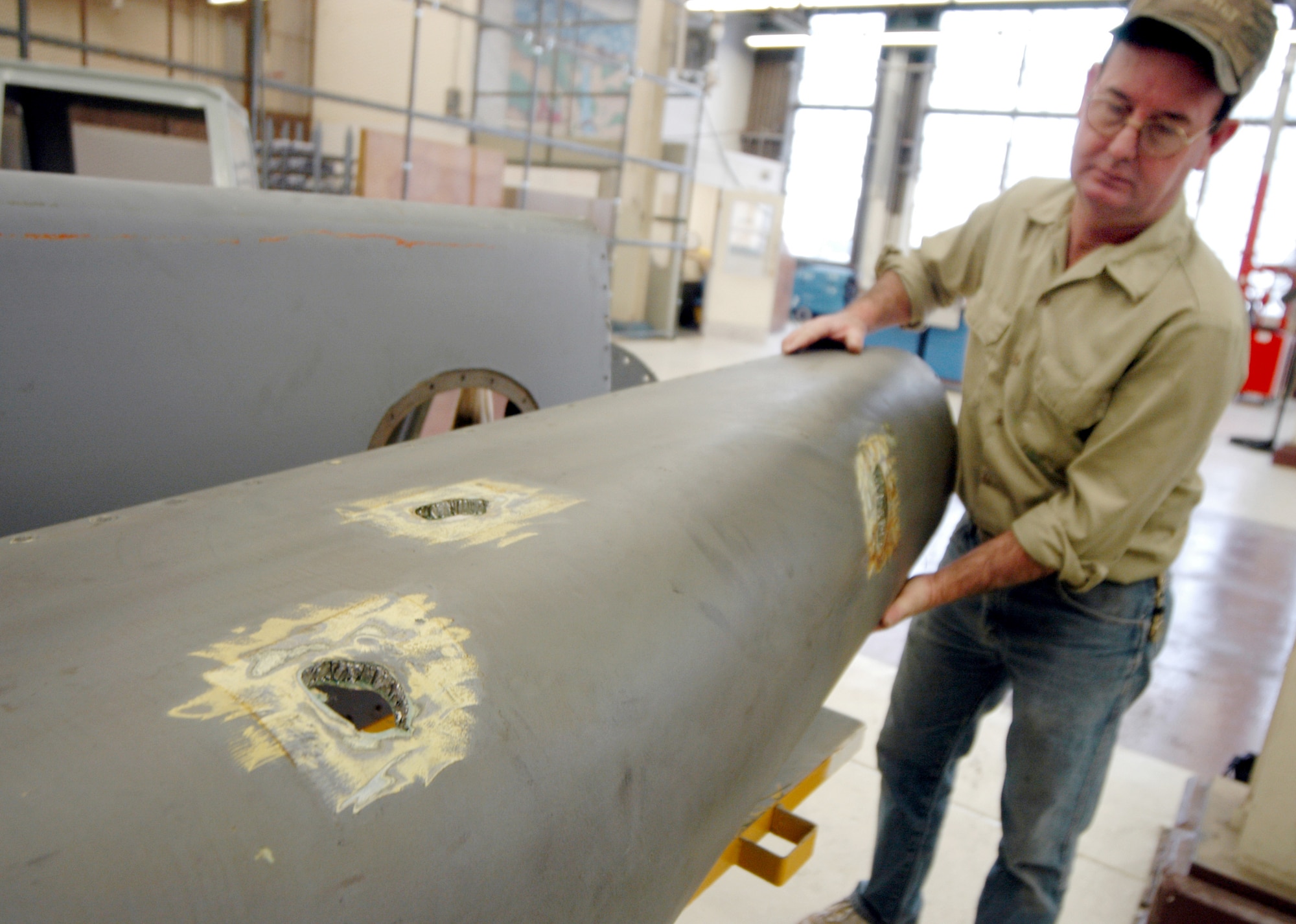 ROBINS AIR FORCE BASE, Ga. -- Wayne Selph shows the damage done to the torque box panel of the C-5 Galaxy that was hit by a missile shortly after takeoff in Iraq on Jan. 8.  The C-5 production branch here made permanent repairs to return the aircraft to Air Mobility Command.  Mr. Selph is a sheet metal mechanic.  (U.S. Air Force photo by Sue Sapp)