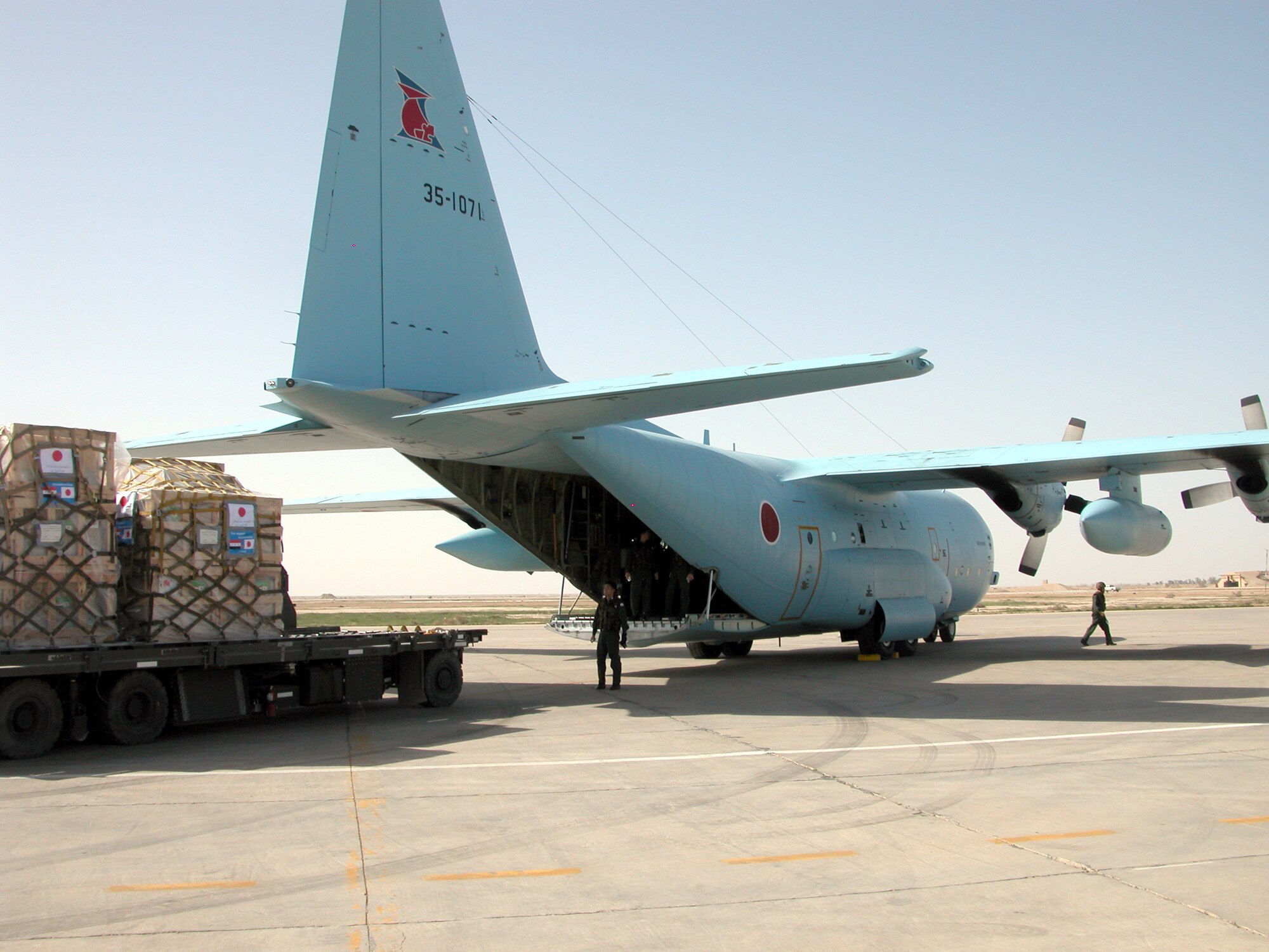 TALLIL AIR BASE, Iraq -- A Japanese C-130 sits empty on the tarmac here March 3 as a cargo loader backs away with more than 5,000 pounds of humanitarian supplies.  (U.S. Air Force photo by Tech. Sgt. Bob Oldham)