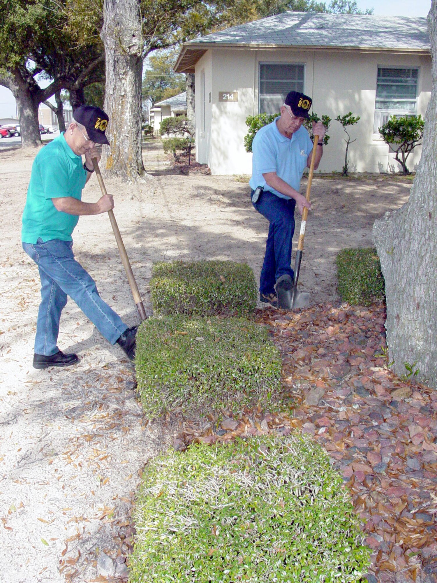 EGLIN AIR FORCE BASE, Fla. -- Peter McMullen and Sam Morgan clear a planter and bushes from the base of a tree here. Surfacing roots are a warning sign of tree stress and suffocation.  The men are both 796th Civil Engineer Squadron grounds supervisors.  (U.S. Air Force photo by Doris Johnson)
