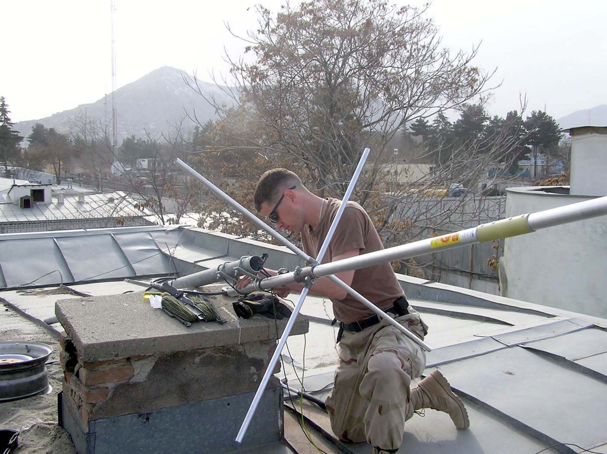 KABUL, Afghanistan -- Staff Sgt. Vincent Bess maintains an antenna on the roof of the Army's Criminal Investigative Division's personal security detail element here.  After installing a new repeater system and setting up the antenna, the improved radio communications helped provide better security for convoys rolling in and out of the Afghanistan capital.  Sergeant Bess is a ground-radio technician with the 455th Expeditionary Operations Group at Bagram Air Base, Afghanistan.  (U.S. Air Force photo by Staff Sgt. Andre Locust)