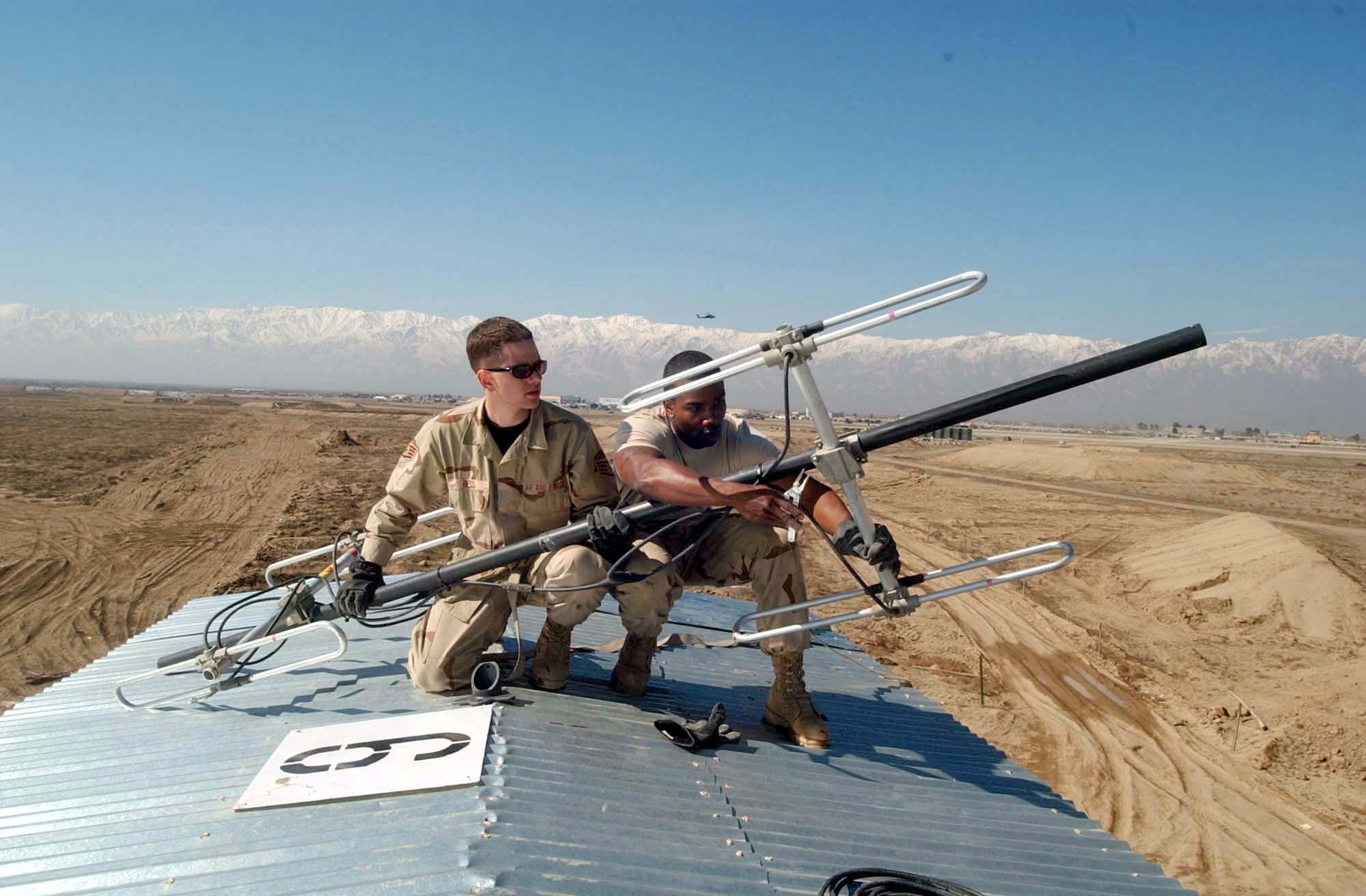 BAGRAM AIR BASE, Afghanistan -- Staff Sgts. Vincent Bess (left) and Andre Locust install a radio-communications antenna for a secondary repeater for the security forces squadron here.  The repeater increased radio coverage so that security forces can now communicate with each other anywhere on the base.  Both Airmen are assigned to the 455th Expeditionary Operations Group's expeditionary communications flight, and they are deployed from the Cryptologic Systems Group at Lackland Air Force Base, Texas.  (U.S. Air Force photo by Tech. Sgt. Brian Davidson)