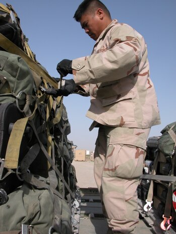 TALLIL AIR BASE, Iraq -- Senior Airman Timothy Abiera tightens down baggage on a pallet before it is loaded onto an aircraft March 10.  Air transportation Airmen have been moving people in and out of the base as the Air Force's air and space expeditionary force rotation hits full swing.  Airman Abiera is an air transportation journeyman deployed here from Charleston Air Force Base, S.C.  (U.S. Air Force photo by Tech. Sgt. Bob Oldham)