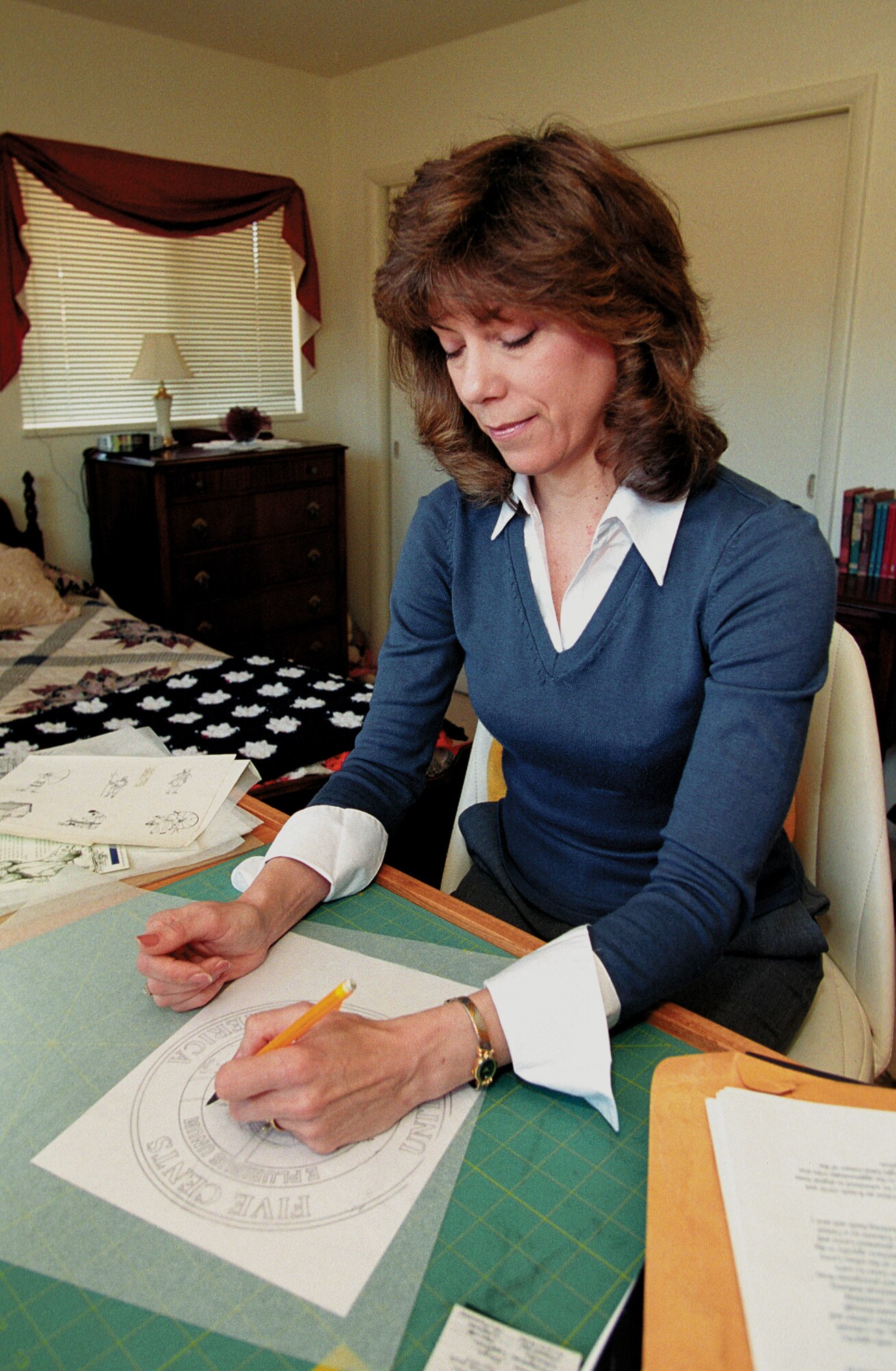 TINKER AIR FORCE BASE, Okla. -- Susan Gamble is one of 24 artists selected to submit designs for a new nickel, the first change to the coin in 66 years.  Mrs. Gamble works at a drafting table at home here after doing initial design work on her computer.  She is the wife of Col. Michael Gamble, the 72nd Air Base Wing Mission Support Group commander here. (U.S. Air Force photo by Margo Wright)