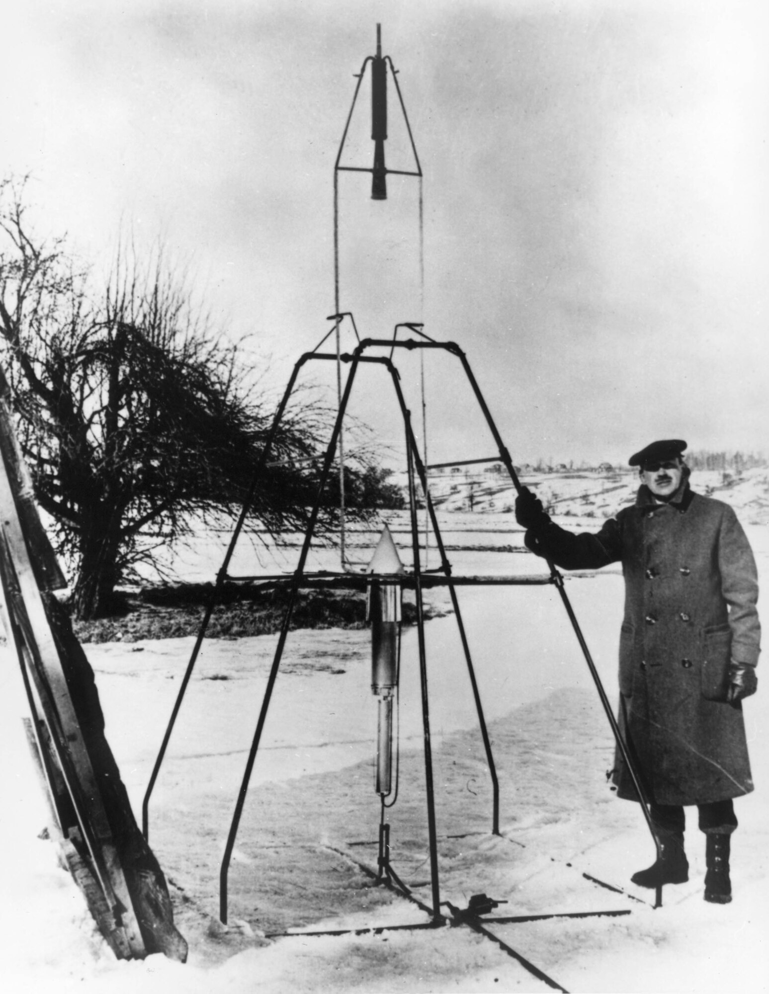 EARLY YEARS -- Robert H. Goddard besides 1926 liquid- fueled rocket. The rocket is on top, receiving its fuel by two lines from the tank at the bottom. Goddard's rockets made little impression upon government officials at the time. (U.S. Air Force photo)