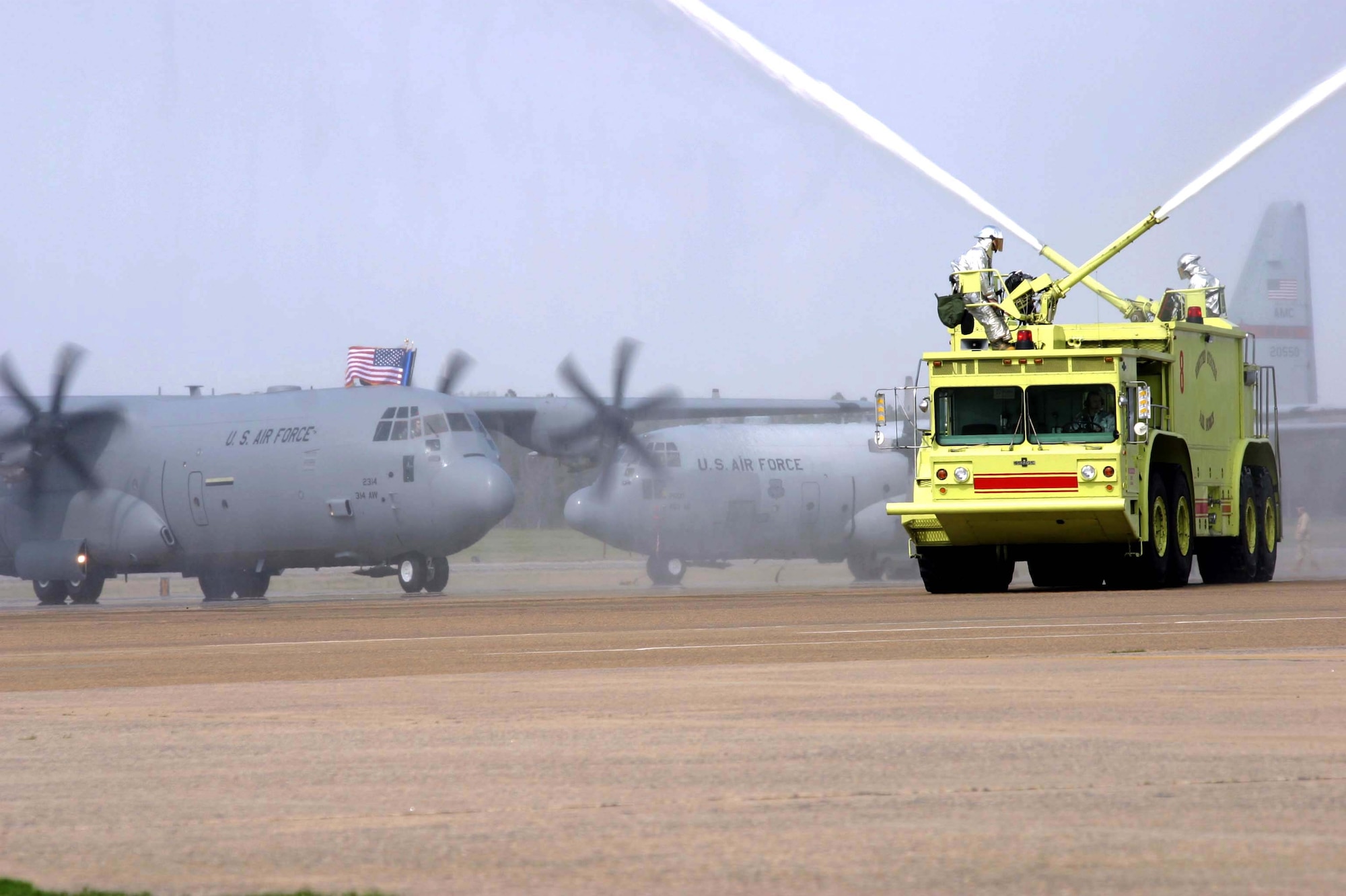 LITTLE ROCK AIR FORCE BASE, Ark. -- The Air Force's first newest C-130J Hercules taxis on the flightline here while a fire truck welcomes the aircraft with a two-water cannon salute March 19.  The new transport arrived after flying from the Lockheed Martin production plant on Dobbins Air Reserve Base, Ga.  It is the first J model assigned to an active-duty unit.  (U.S. Air Force photo by Senior Airman Jason A. Neal)