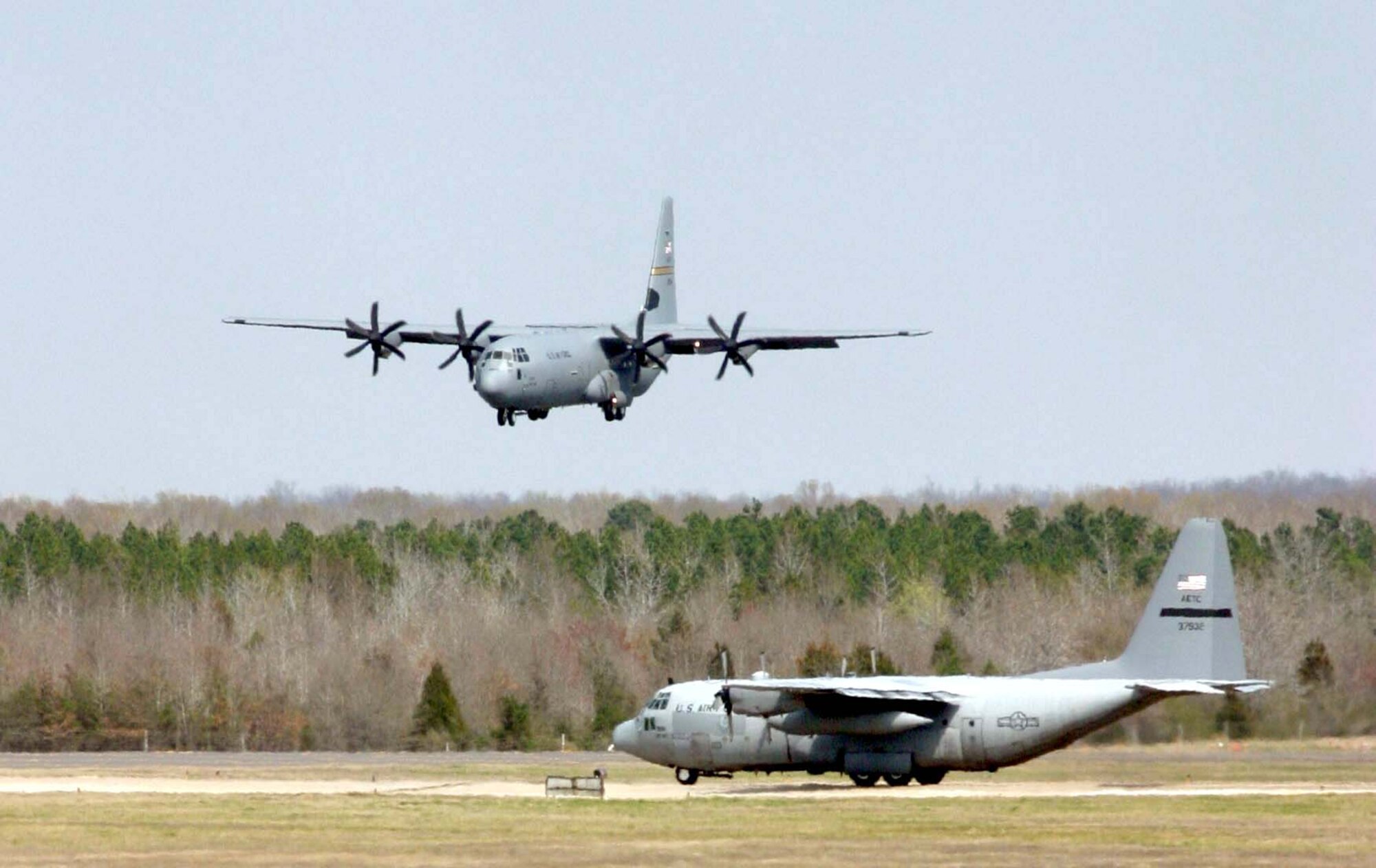 LITTLE ROCK AIR FORCE BASE, Ark. -- The Air Force's newest C-130J Hercules comes in for a landing here March 19 while an older C-130 model waits on the runway.  This is the first J model assigned to an active-duty unit.  (U.S. Air Force photo by Senior Airman Jason A. Neal)