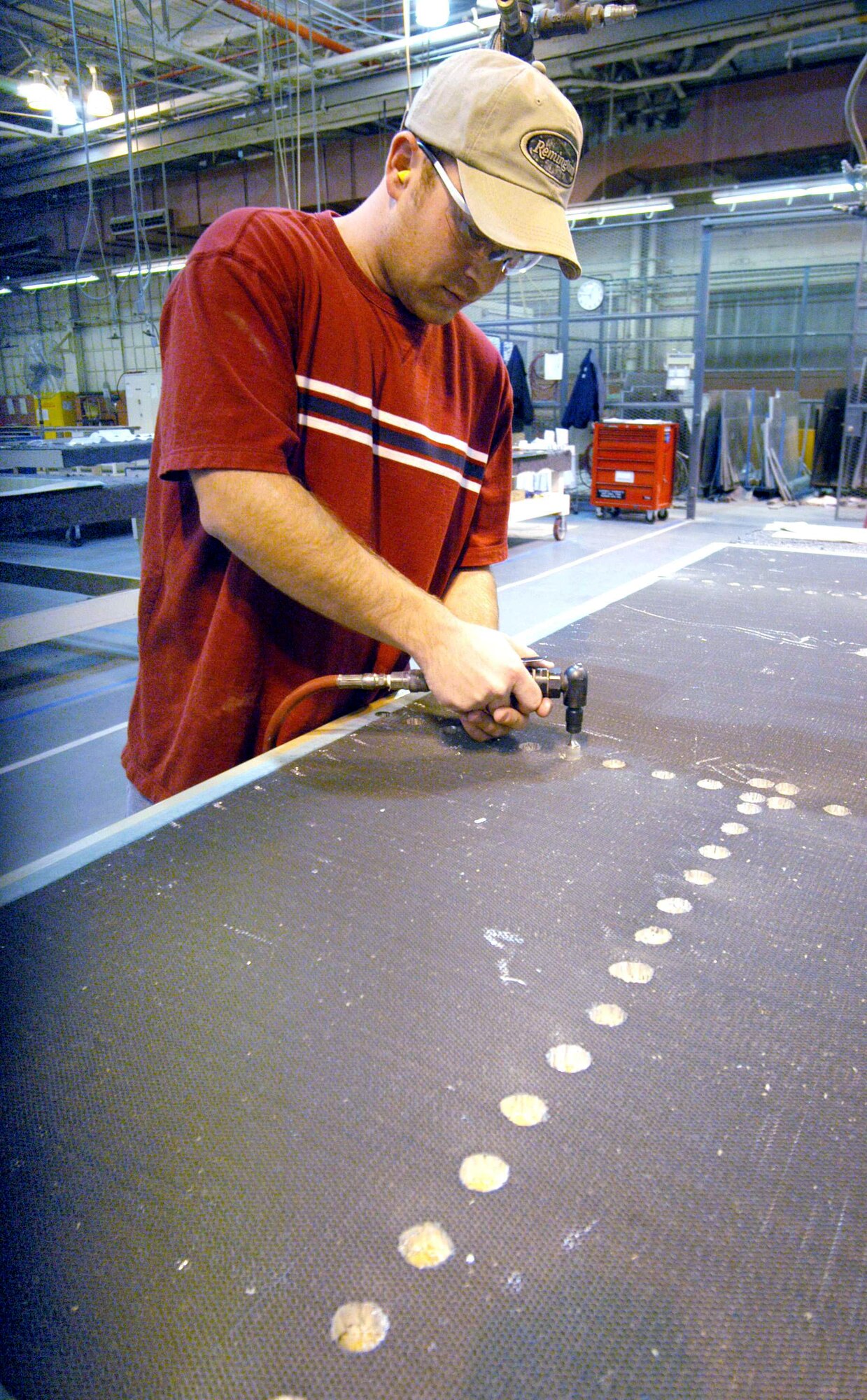 ROBINS AIR FORCE BASE, Ga. -- Heath Rowland routs out the honeycomb core of a C-5 Galaxy floorboard for fastener locations.  Mechanics here found that making new aircraft floorboards rather than repairing used ones saved nearly $5.5 million per year.  Mr. Rowland is a sheet metal mechanic.  (U.S. Air Force photo by Sue Sapp)