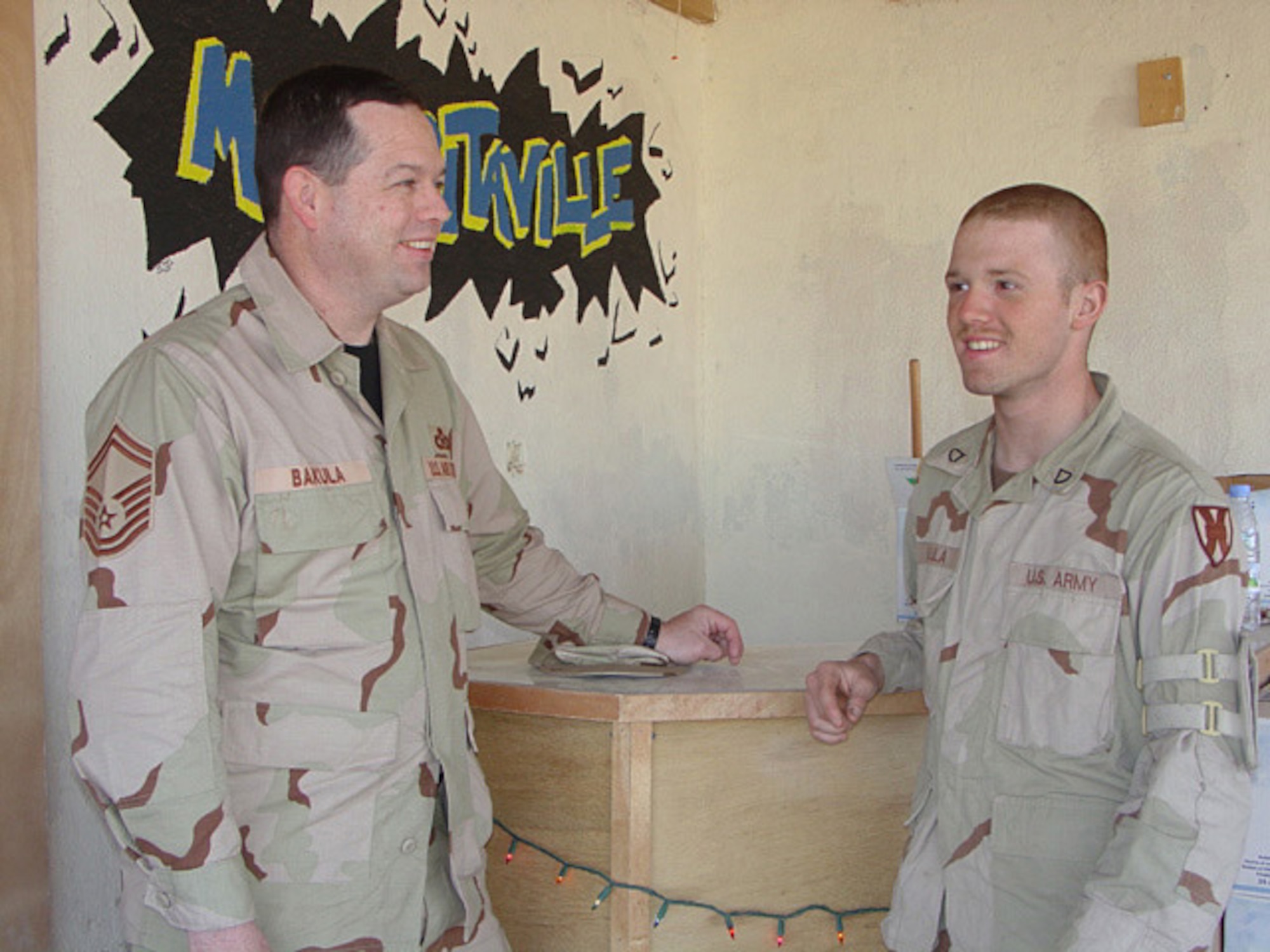 TALLIL AIR BASE, Iraq -- Senior Master Sgt. Lawrence Bakula (left) and his son, Army Pfc. James Bakula, reunite here briefly.  Sergeant Bakula is the superintendent of the command post, and Private Bakula is deployed with the 66th Transportation Company.  (U.S. Air Force photo by Capt. Susan A. Romano)