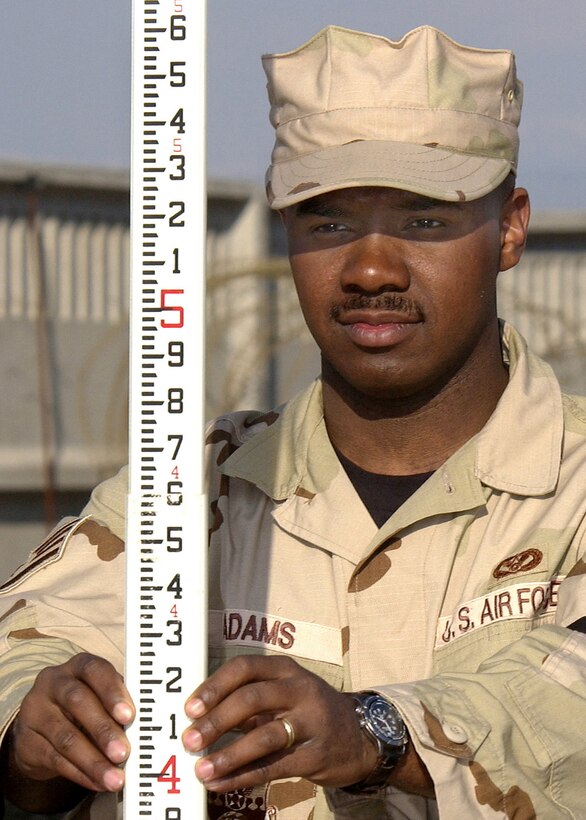 MANAS AIR BASE, Kyrgyzstan -- Staff Sgt. Tyler Adams holds a measuring stick to ensure the proper ground grade is complete at the fuels farm construction site here.  Sergeant Adams and other Airmen of the 376th Expeditionary Civil Engineer Squadron will move more than 63 million pounds of dirt by the end of the project.  He is deployed from Ellsworth Air Force Base, S.D.  (U.S. Air Force photo by James Westfall)