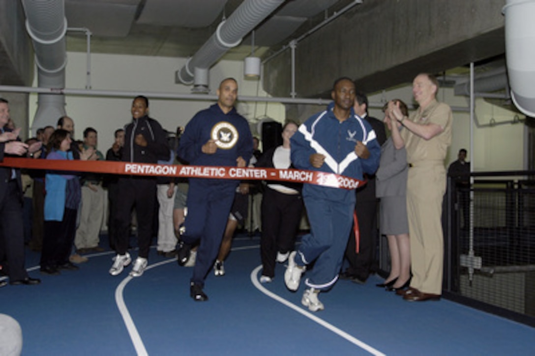 Three-time Olympic Gold Medalist and five-time track and field world champion Marion Jones (left) and Department of Defense representatives finish the first ceremonial lap around the new Pentagon Athletic Center indoor running track on March 29, 2004. 