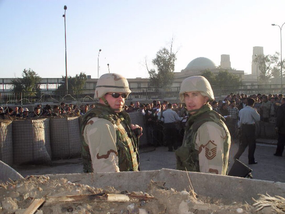 IRAQ -- Capt. Pete Ellum (left) and Master Sgt. Greg Elmore wait outside a recruiting station here.  They are recruiting for the Iraqi armed forces, border patrol, police force, facilities-protection service and other agencies here.  Captain Ellum is deployed from the 319th Recruiting Squadron at Portsmouth, N.H.  Sergeant Elmore is from Air Force Recruiting Service at Randolph Air Force Base, Texas.  (Courtesy photo)
