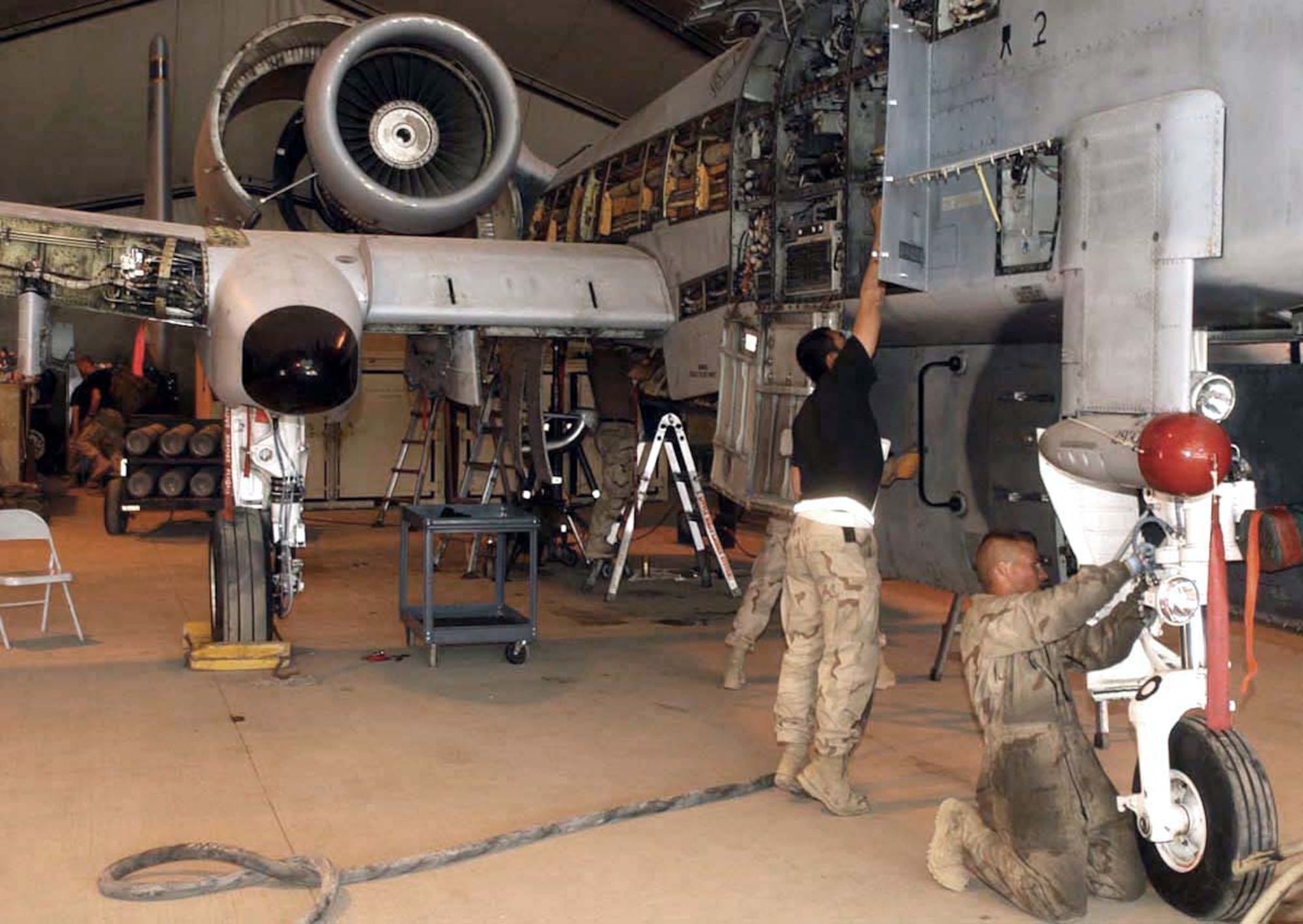 BAGRAM AIR BASE, Afghanistan -- Airman 1st Class Daniel Hanamoto (standing) inspects an electro-environmental component on an A-10 Thunderbolt II while Senior Airman Shane Neel installs a nose wheel steering cover to the aircraft.  Both Airmen are assigned to the 455th Expeditionary Aircraft Maintenance Squadron.  (U.S. Air Force photo by Master Sgt. Jeff Szczechowski)