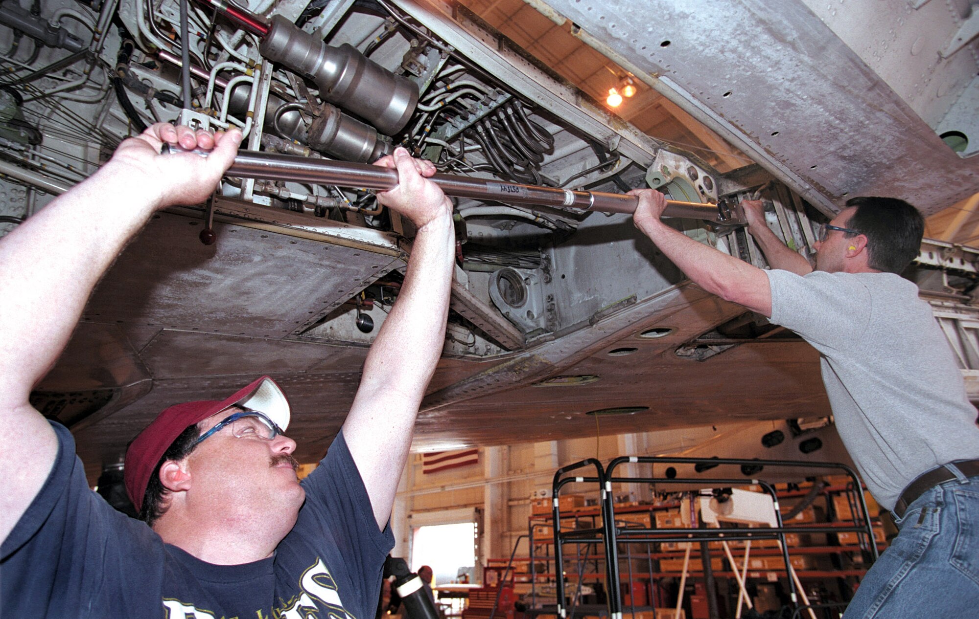 TINKER AIR FORCE BASE, Okla. -- Jerry Byke (left) and Steve LaPlume loosen main landing gear trunnion bolts so the men can inspect for corrosion.  Mr. Byke is a hydraulics aircraft mechanic, and Mr. LaPlume is a flight controls aircraft mechanic.  (U.S. Air Force photo by Margo Wright)