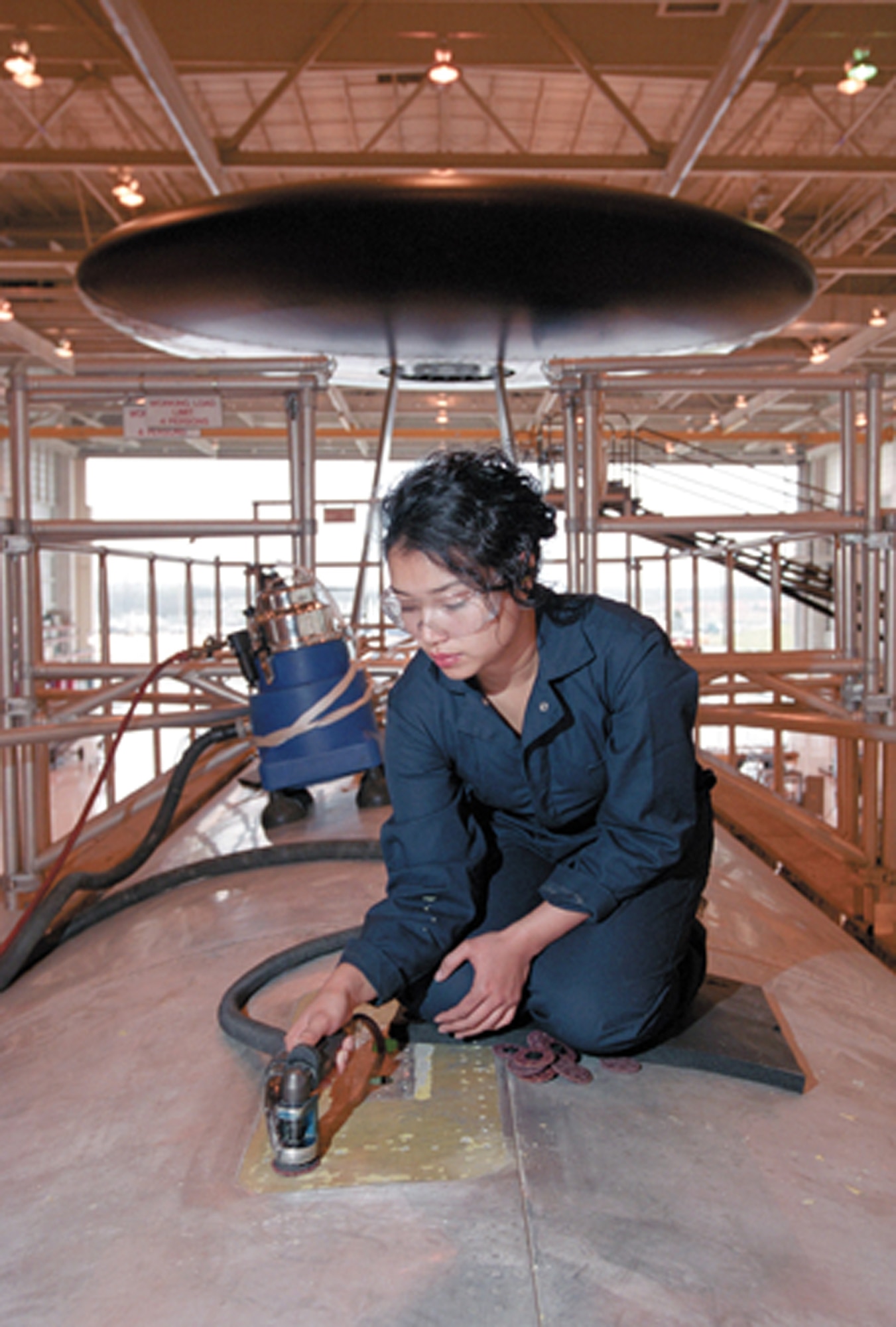 TINKER AIR FORCE BASE, Okla. -- Edith Clemons, a sheet-metal mechanic, attacks corrosion on an E-3 Sentry undergoing depot maintenance.  The areas where three satellite-communications antennas attach to the aircraft are always inspected for corrosion.  (U.S. Air Force photo by Margo Wright)