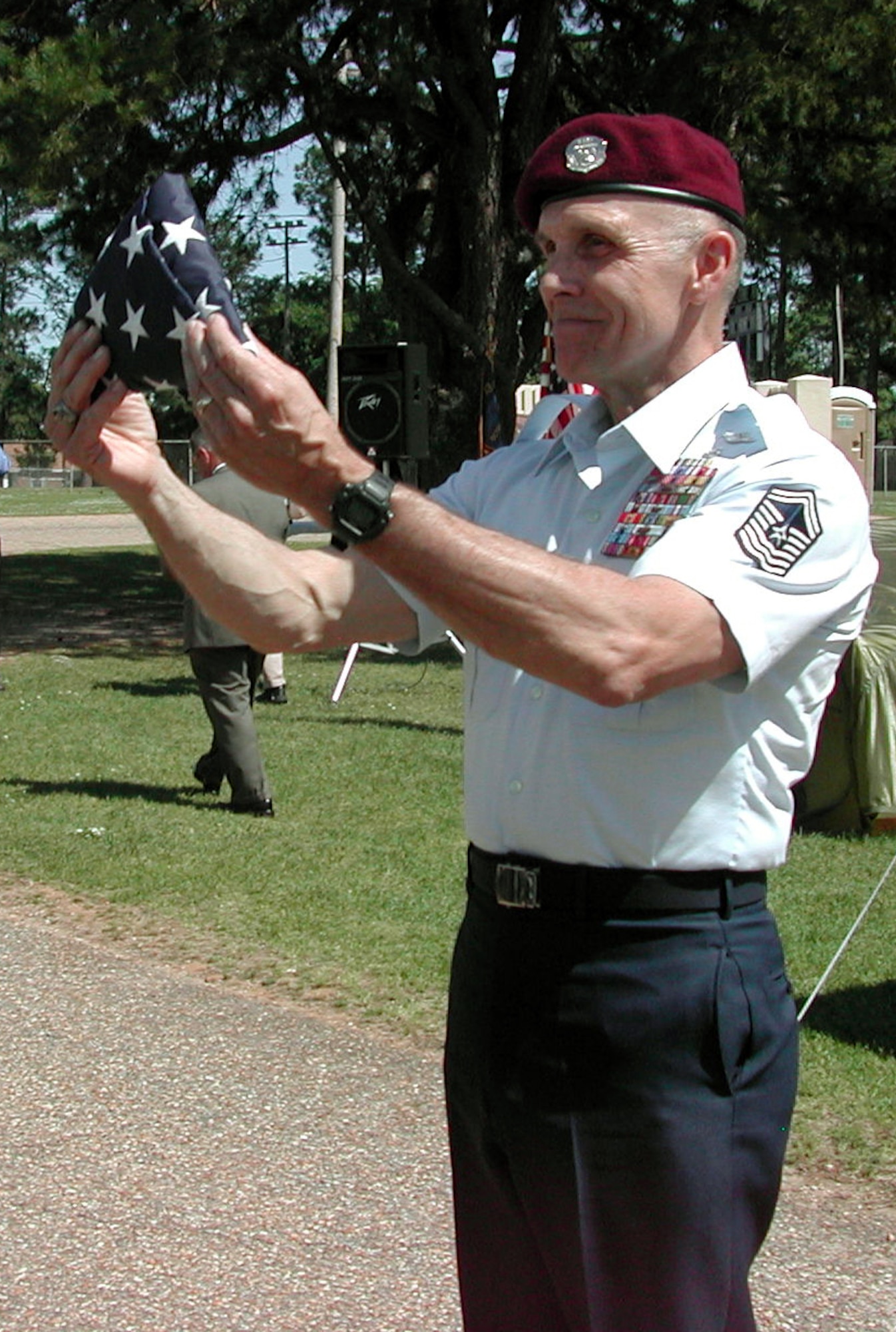 MAXWELL AIR FORCE BASE, Ala. -- Retired Chief Master Sgt. Wayne Fisk displays a flag presented to him by two pararescue Airmen who rappelled from a helicopter during a ceremony naming a park here in his honor April 28.  (U.S. Air Force photo by Carl Bergquist)