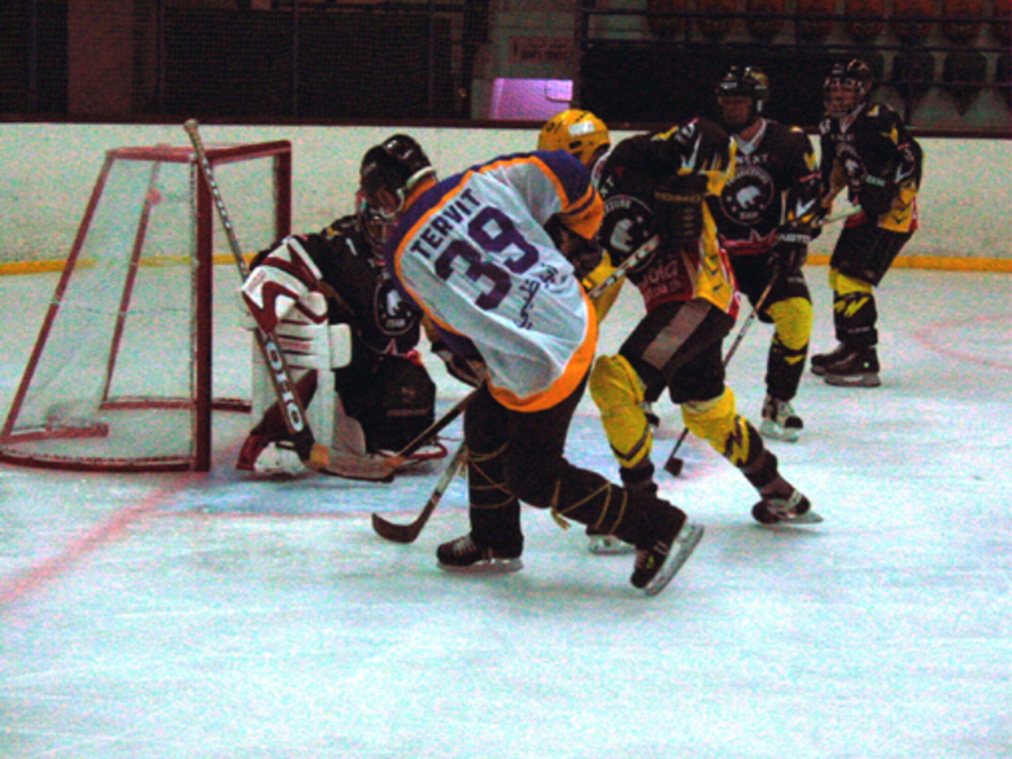 SOUTHWEST ASIA -- Senior Master Sgt. Daniel Morin, in the white jersey, takes a shot on goal during one of his team's ice hockey tournament games.  He had to borrow a teammate's jersey to be able to play, thus the different name on his back.  He is the 380th Expeditionary Maintenance Operations Squadron's quality assurance superintendent at a forward-deployed location.  (U.S. Air Force photo by Senior Airman Matthew Bates)