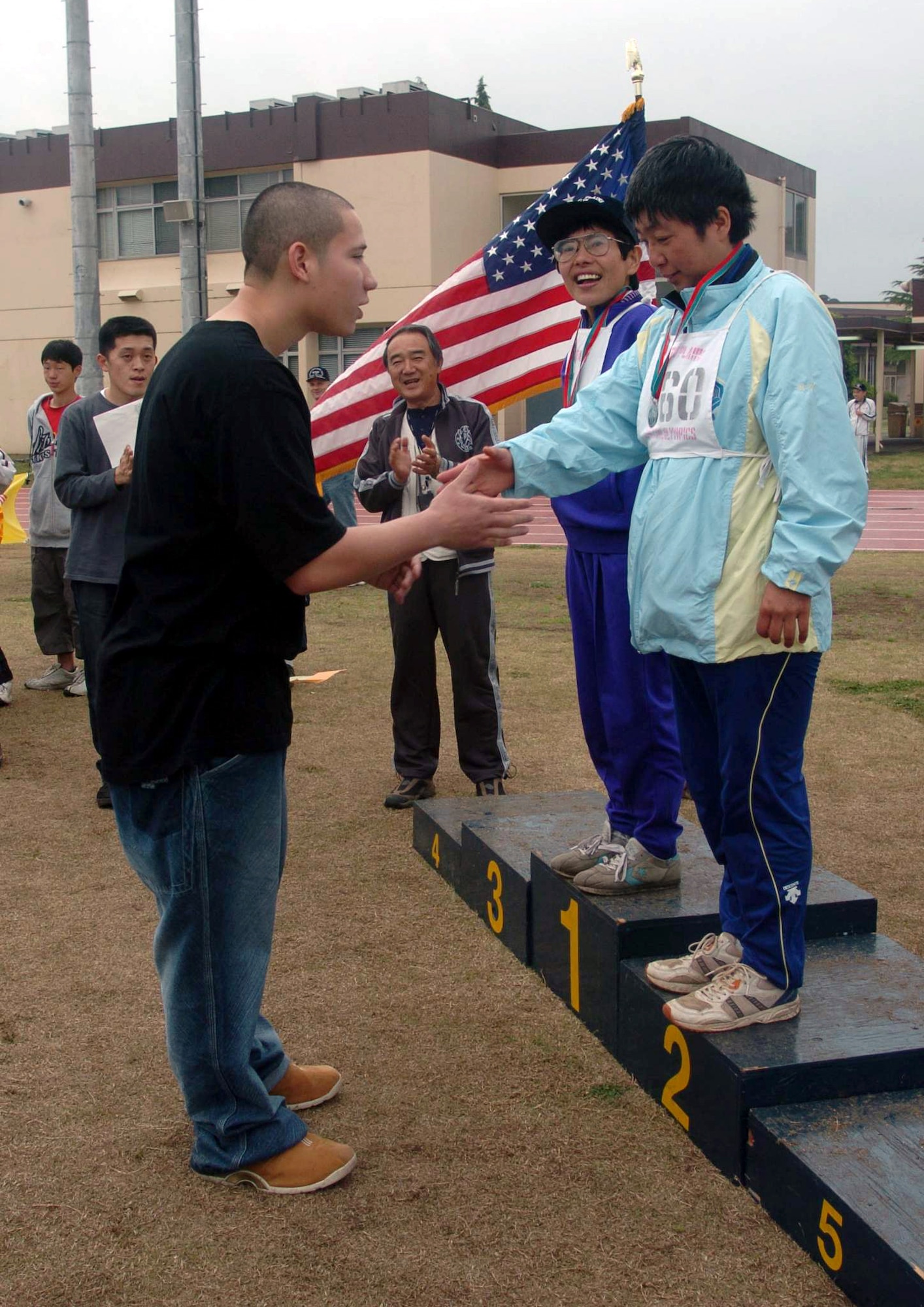 YOKOTA AIR BASE, Japan -- Airman Christian Garcia shakes hands with a Japanese athlete during a medal presentation at the 25th annual Kanto Plains Special Olympics here May 9.  More than 500 athletes participated in the games.  Airman Garcia is assigned to the 374th Dental Squadron.  (U.S. Air Force photo by Master Sgt. Val Gempis)