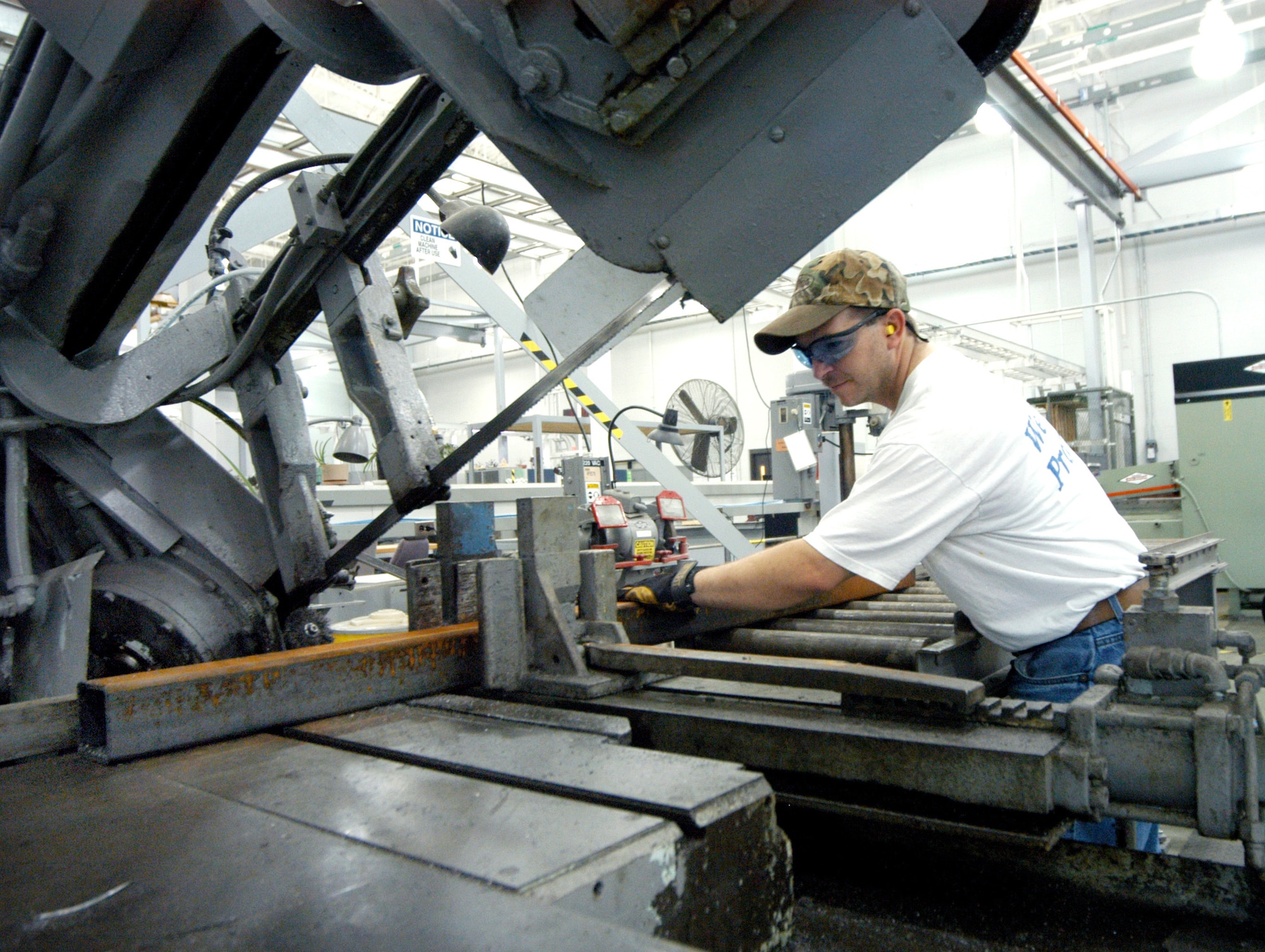ROBINS AIR FORCE BASE, Ga. -- Ashley Holder slides metal guard-rail tubing onto a saw.  Mr. Holder is a millwright, or metal structure mechanic, here. (U.S. Air Force photo by Sue Sapp)