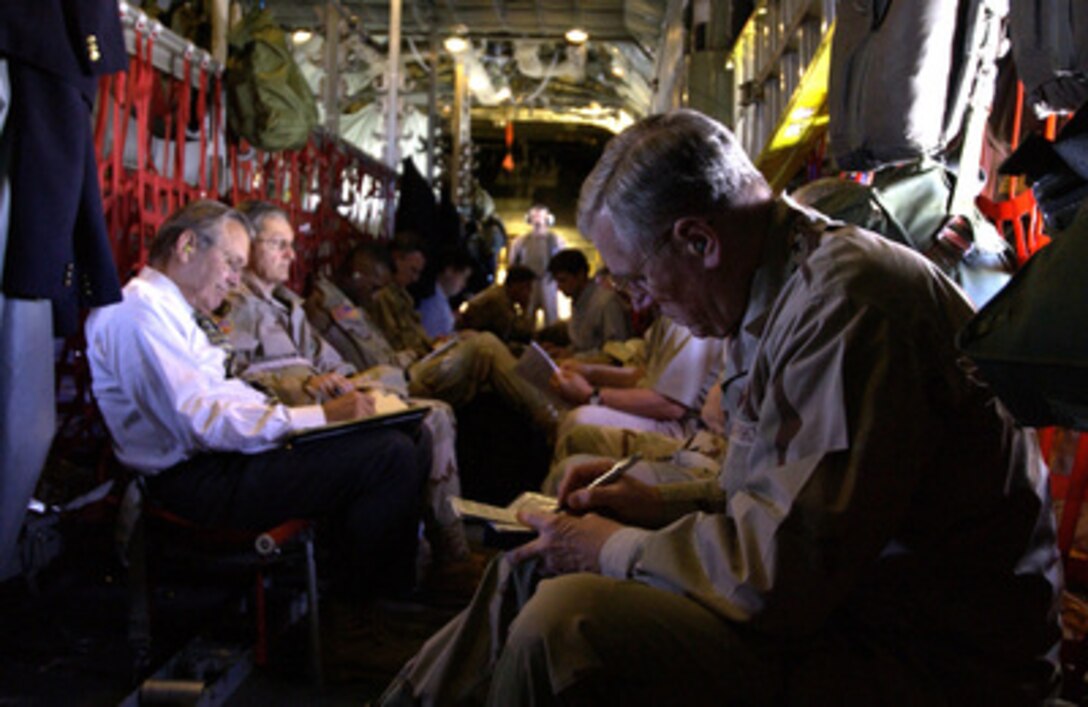 Chairman of the Joint Chiefs of Staff Gen. Richard B. Myers looks over some briefings while Secretary of Defense Donald H. Rumsfeld does the same aboard a Texas Air National Guard C-130E headed for Baghdad, Iraq, on May 13, 2004. Rumsfeld and Myers are traveling to Southwest Asia to visit the troops in Baghdad. 