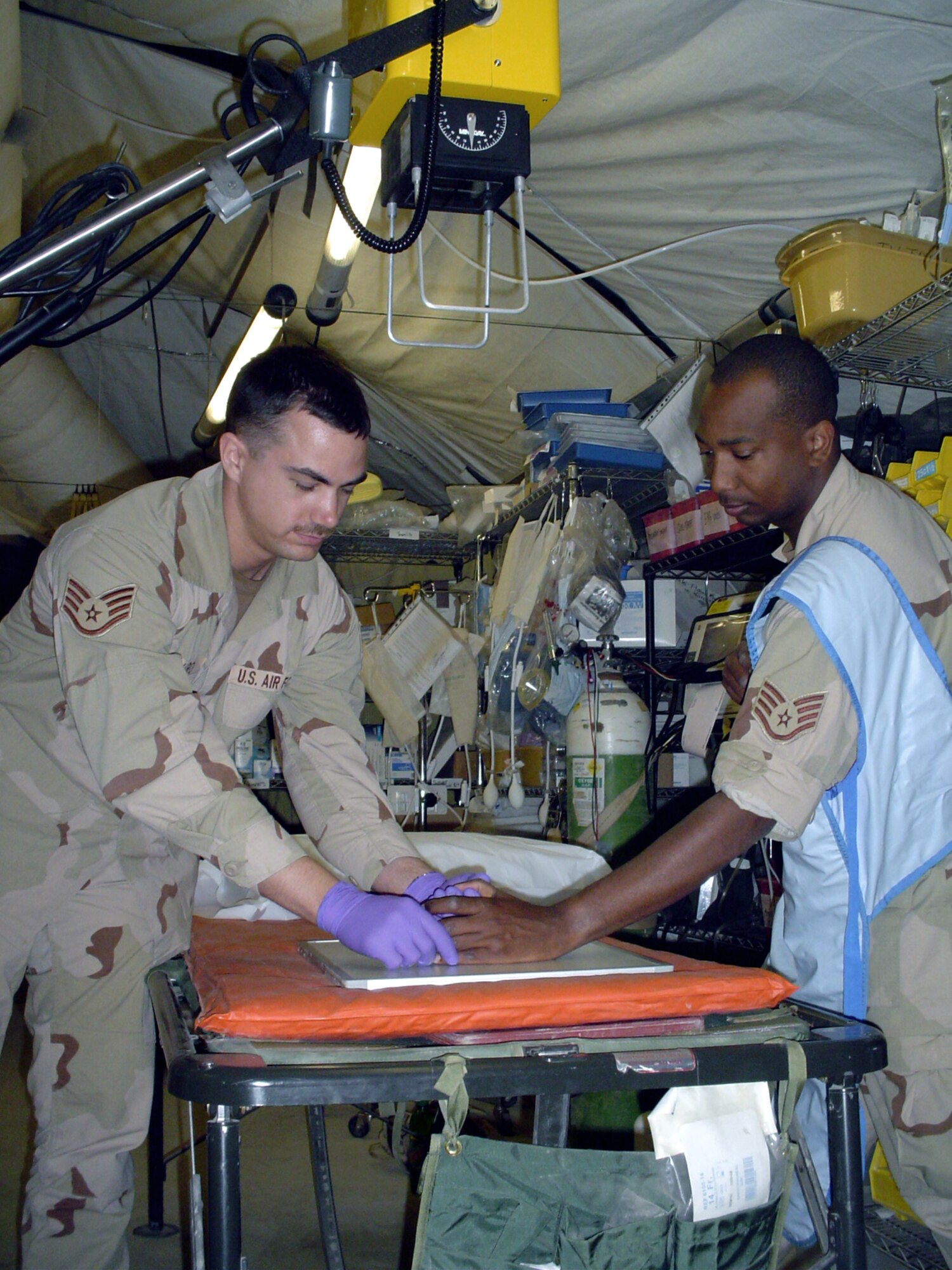 CAMP SATHER, Iraq -- Staff Sgt. Dan Schiro (left) sets up an X-ray shot of Staff Sgt. Fitzroy Munroe's hand using a field portable X-ray unit.  Sergeant Schiro is a medical technician with the 447th Expeditionary Medical Squadron.  Sergeant Munroe is a dental technician with the squadron.  (U.S. Air Force photo by Master Sgt. Sean E. Cobb)