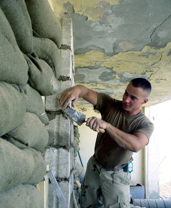 TALLIL AIR BASE, Iraq -- Airman 1st Class Ryan Heath installs concrete blocks over windows here May 17.  The blocks are replacing sandbags as part of improvements.  Airman Heath is with the 407th Expeditionary Civil Engineer Squadron supporting Operation Iraqi Freedom. (U.S. Air Force photo by Tech. Sgt. Carrie Bernard)