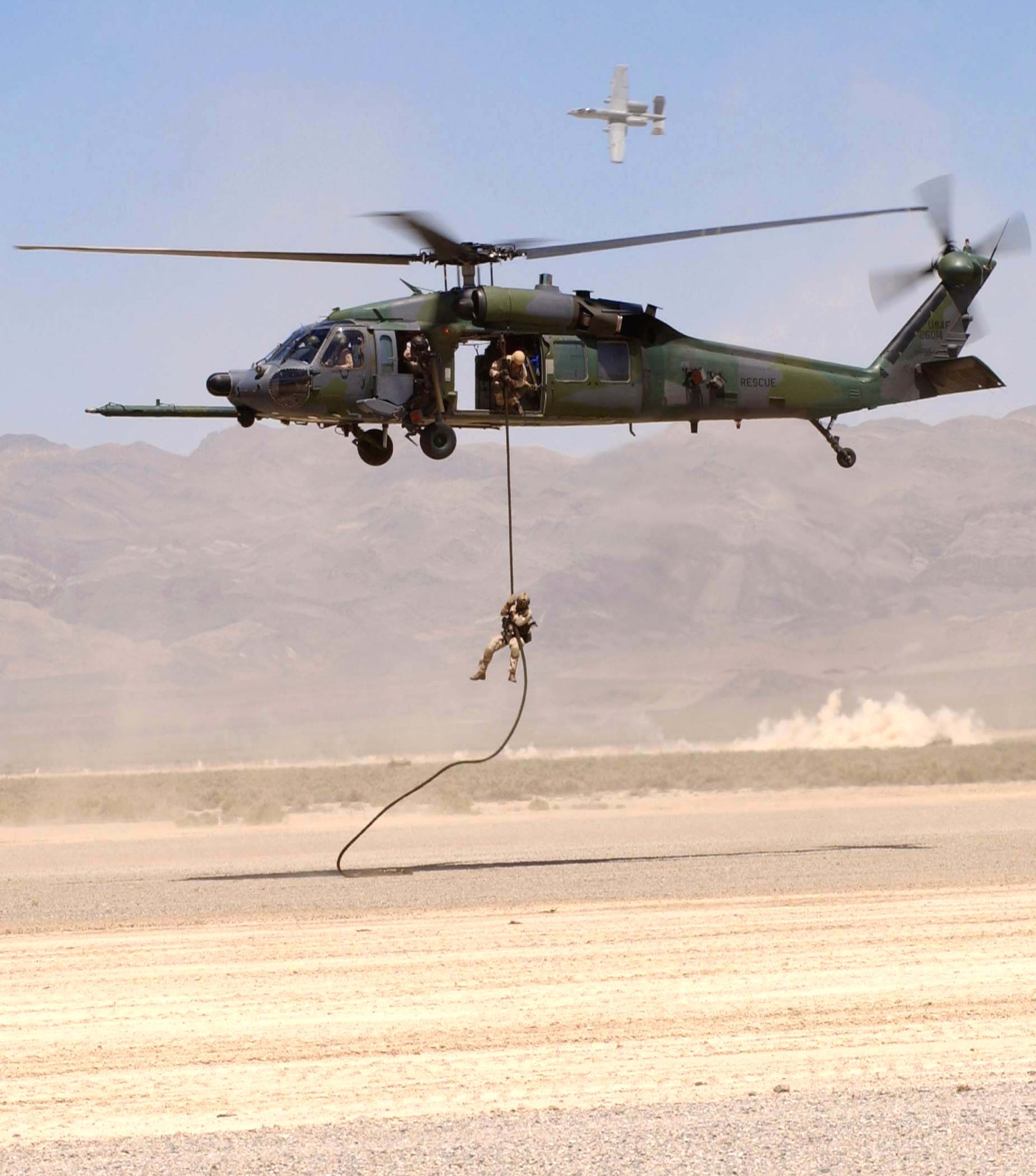 NELLIS AIR FORCE BASE, Nev. -- An Airmen of the 66th Rescue Squadron rappels from an HH-60G Pave Hawk helicopter as A-10 Thunderbolt IIs lay cover fire during an Air Force firepower demonstration near here May 12.  The demonstration showcases the Air Force's air and space capabilities.  (U.S. Air Force photo by Staff Sgt. William Juergen)