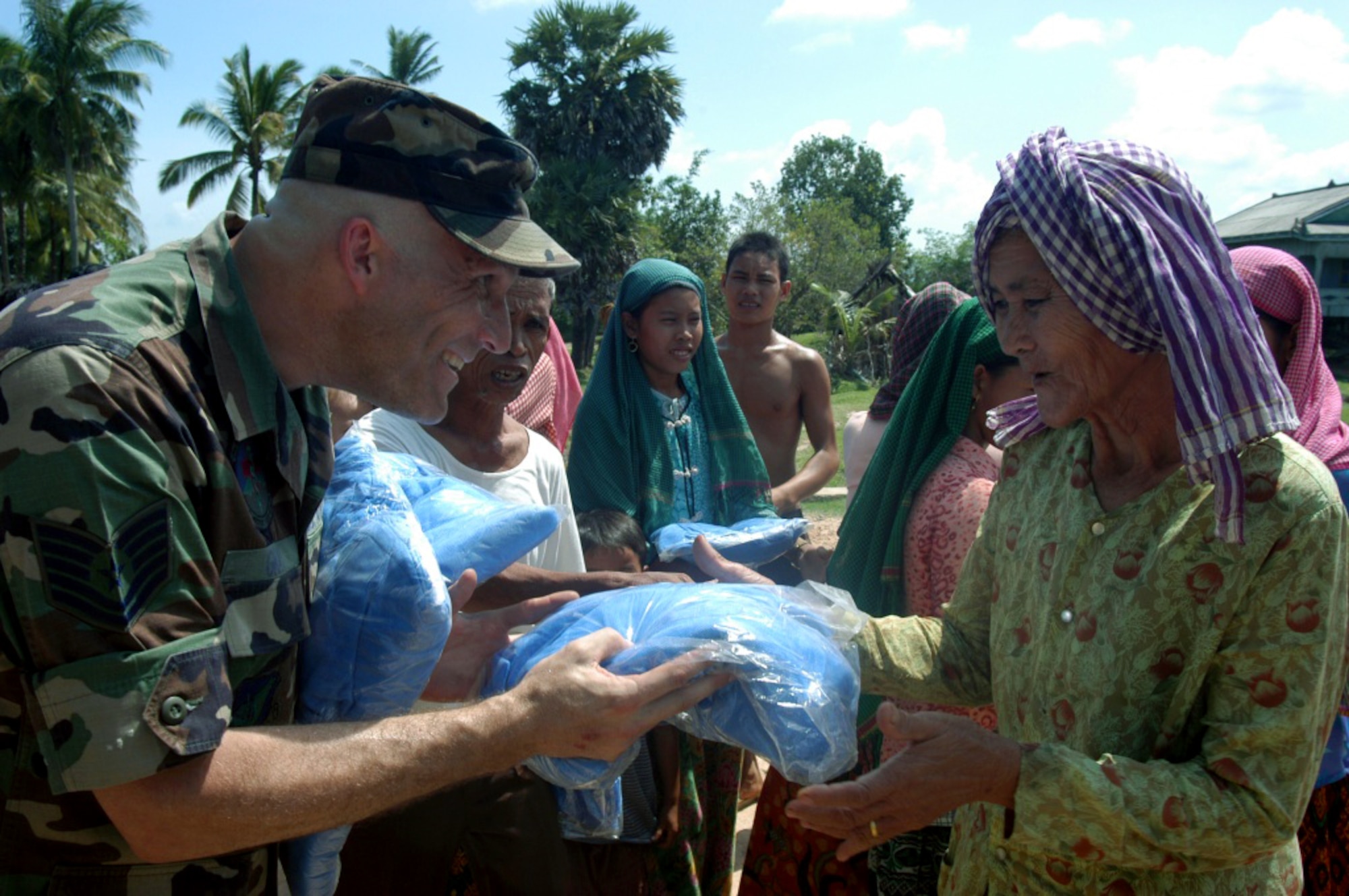 KEP, Cambodia -- Tech. Sgt. Bryan Gray hands out mosquito nets to a Cham-Muslim woman in a village near here May 20.  He is part of a 20-person blast resuscitation and victim assistance team on a two-week humanitarian mission.  Members of the team are passing out 1,000 mosquito nets to cut down on malaria.  Sergeant Gray is a biomedical equipment repair technician with the 18th Medical Support Squadron at Kadena Air Base, Japan.  (U.S. Air Force photo by Master Sgt. Adam Johnston)