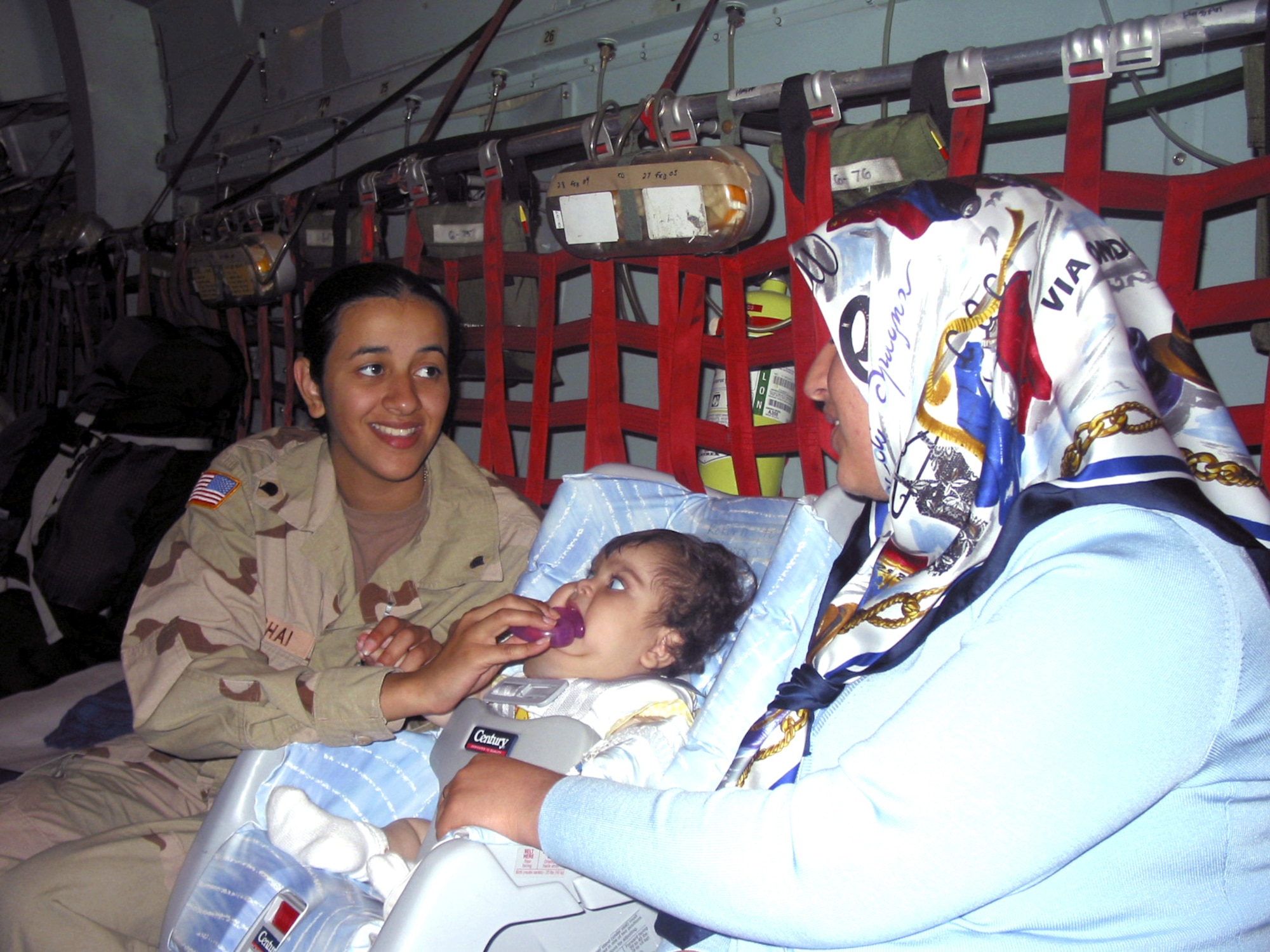 RAMSTEIN AIR BASE, Germany -- Army Spc. Mariana Beshai cares for 8-month-old Fatemah Khalil Hassan while talking to her mother, Beyda'a Amir Abdul Jabar, here May 19.  The Iraqi child was flown to the United States where she will undergo specialized treatment at Children's Hospital in Columbus, Ohio.  Specialist Beshai is assigned to the Army National Guard's 230th Support Battalion stationed in Iraq.  (U.S. Air Force photo by 1st Lt. Tracy Giles)