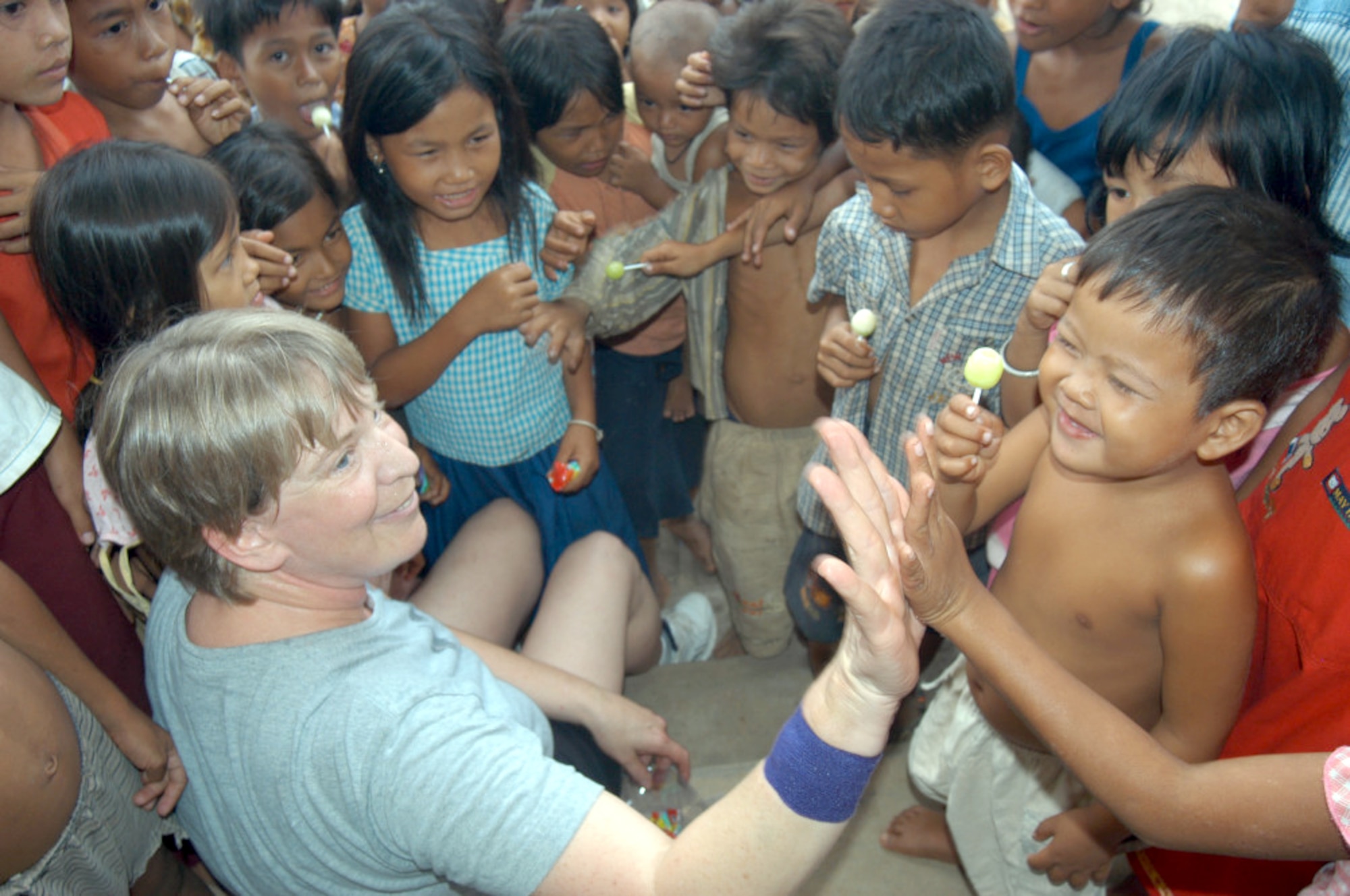 KEP, Cambodia -- Master Sgt. Rita Greiner gives a high-five after handing out a lollipop to a Cambodian boy as more Cambodian children gather in a hospital compound here May 22.  Sergeant Greiner is an orthopedics technician and is part of a 20-person blast resuscitation and victim assistance team.  She is assigned to the 99th Medical Operations Squadron at Nellis Air Force Base, Nev.  (U.S. Air Force photo by Master Sgt. Adam Johnston)