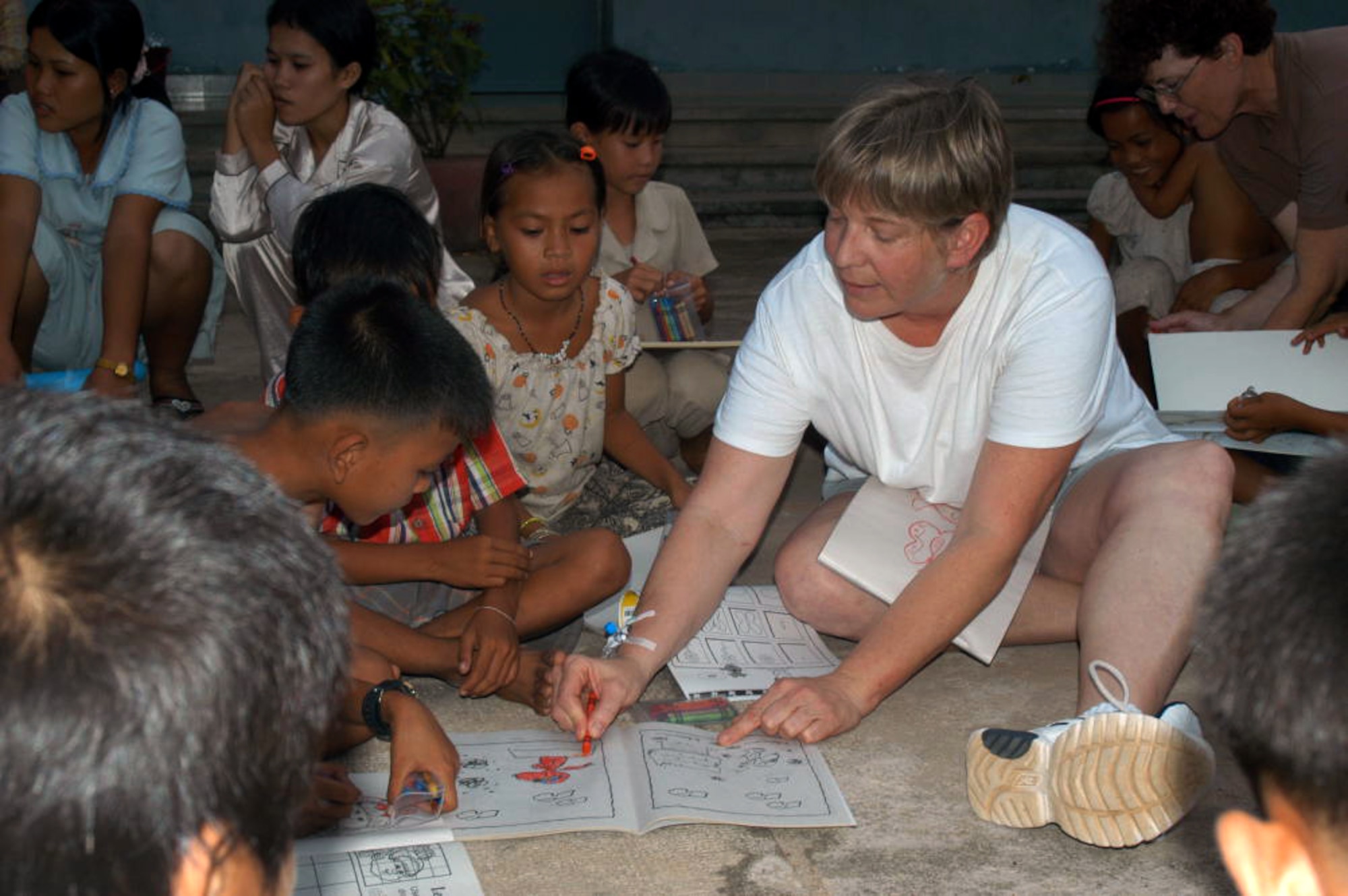 KEP, Cambodia -- Master Sgt. Rita Greiner leads a coloring book session with Cambodian children in a hospital compound here May 21.  Sergeant Greiner is an orthopedics technician and is part of a 20-person blast resuscitation and victim assistance team.  She is assigned to the 99th Medical Operations Squadron at Nellis Air Force Base, Nev.  (U.S. Air Force photo by Master Sgt. Adam Johnston)