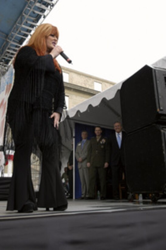 Country music singer Wynonna Judd performs her USO concert at the Pentagon on May 21, 2004. Enjoying the concert from the stage are from left to right: President and Chief Executive Officer of the USO Edward Powell, Vice Chairman of the Joint Chiefs of Staff Gen. Peter Pace, U.S. Marine Corps, and Secretary of Defense Donald H. Rumsfeld. Judd performed for an audience of military and DoD civilians that included military personnel recovering from wounds received in Iraq and Afghanistan. 