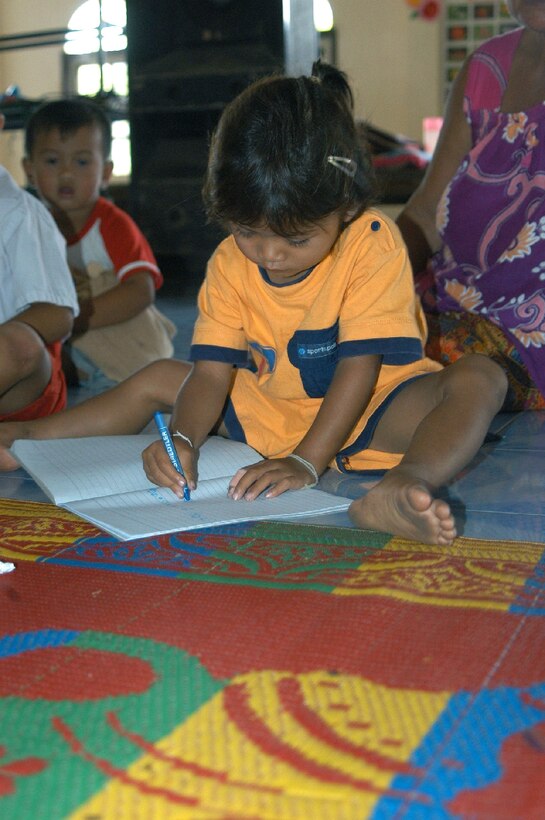 UDORN THANI, Thailand -- A student at a preschool near here loses no time in trying her new crayons and coloring book.  Airmen from the 353rd Special Operations Group at Kadena Air Base, Japan, visited the preschool to donate supplies and improve the playground.  (U.S. Air Force photo by Master Sgt. Michael Farris)