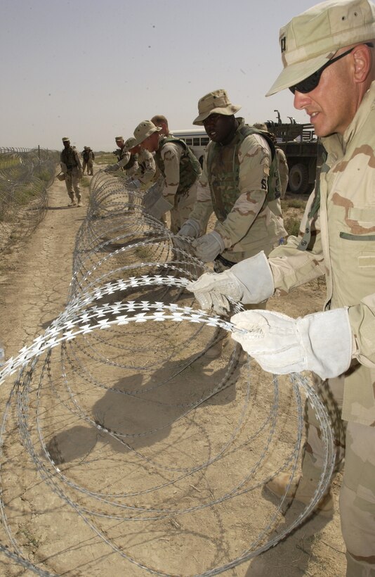 TALLIL AIR BASE, Iraq -- People from the base assist in securing the perimeter by helping to run concertina wire here May 27. (U.S. Air Force photo by Staff Sgt. Christina M. Rumsey)