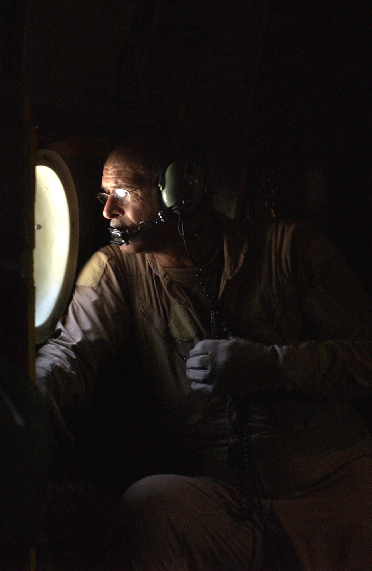 OVER AFGHANISTAN -- Loadmaster Master Sgt. Stanley Johnson scans the terrain of northern Afghanistan as the C-130 Hercules he is flying in passes over mountains. Sergeant Johnson is deployed from the Missouri Air National Guard to Uzbekistan, supporting Operation Enduring Freedom.  (U.S. Air Force photo Master Sgt. Scott Wagers)
