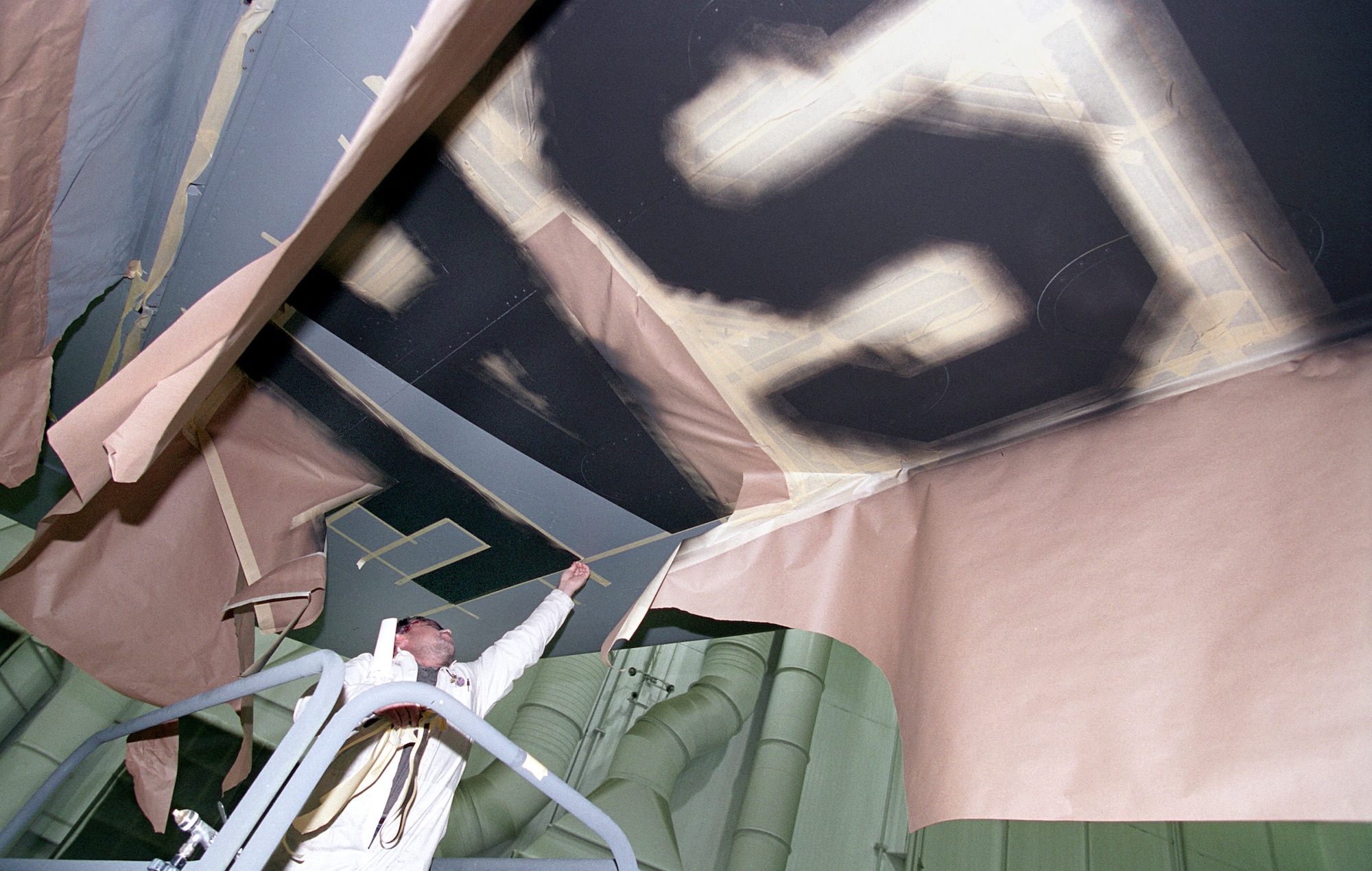 TINKER AIR FORCE BASE, Okla. -- After "USAF" is painted under a KC-135 Stratotanker's wing, Gerald Spurgion removes the paper and tape mask.  (U.S. Air Force photo by Margo Wright)
