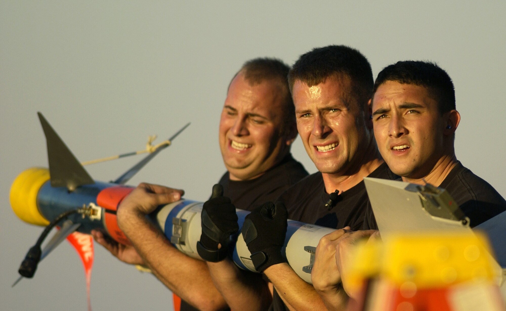 TYNDALL AIR FORCE BASE, Fla. -- (From left) Senior Airman Mike Raimondo, Staff Sgt. Jacob Watson and Airman 1st Class Joseph Ragadio carry an AIM-9M missile to an F-15 Eagle during the static weapons load competition here Nov. 9.  They are weapons loaders assigned to the 71st Fighter Squadron at Langley Air Force Base, Va.  The loading competition is part of William Tell, an air-to-air weapons meet currently under way.  (U.S. Air Force photo by Tech. Sgt. Ben Bloker)
