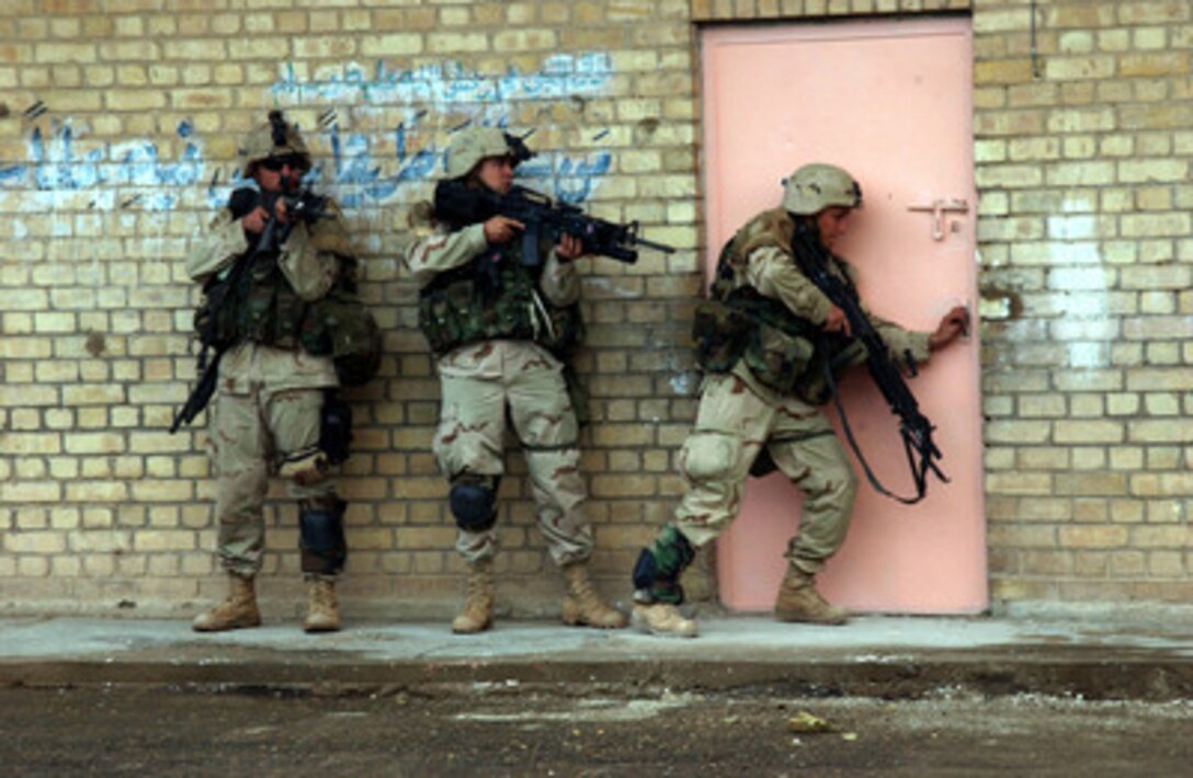 U.S. Army soldiers are poised to enter a building in Fallujah, Iraq, during Operation al Fajr (New Dawn) on Nov. 9, 2004. The soldiers are assigned to 2nd Battalion, 5th Cavalry Regiment, 2nd Brigade Combat Team, 1st Cavalry Division. 