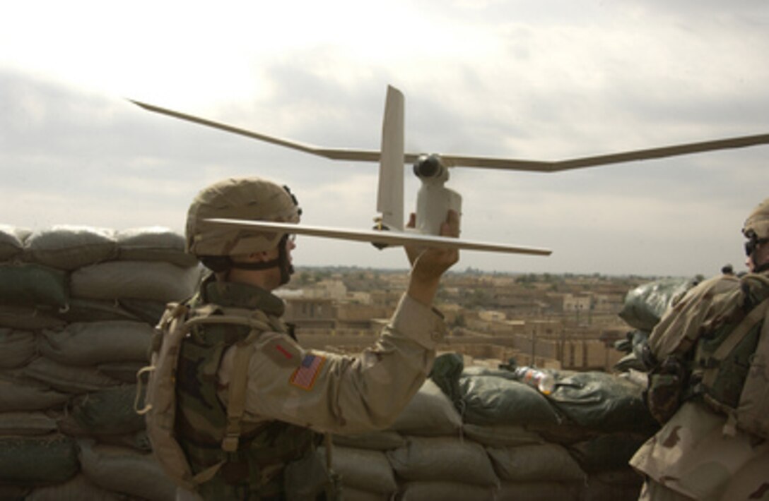 U.S. Army Spc. William Pasiechnik launches a Raven unmanned aerial vehicle to conduct reconnaissance for insurgents attacking Patrol Base Uvanni in Samarra, Iraq, on Nov. 6, 2004. 