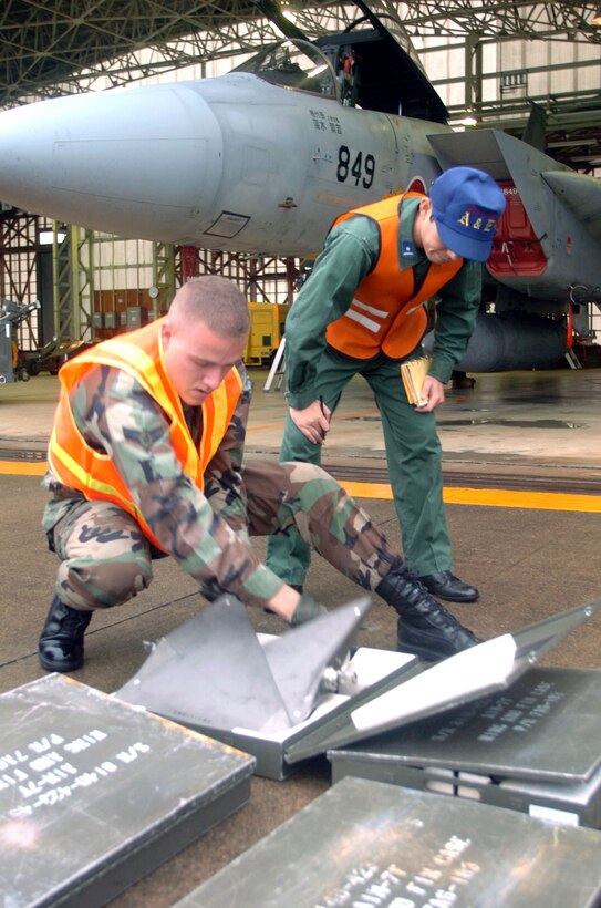 HYAKURI AIR BASE, Japan -- Airman 1st Class Brian Gates (left) prepares to load an AIM-7 Sparrow on a Japanese F-15 aircraft while Japanese 2nd Lt. Mitsuhiro Kawano watches during turn-around familiarization training involving U.S. and Japanese forces.  The training is part of Keen Sword 2005, a defensive readiness exercise.  Airman Gates is an aircraft armament systems specialist from the 18th Maintenance Group at Kadena Air Base, Japan.  (U.S. Air Force photo by Master Sgt. Val Gempis)