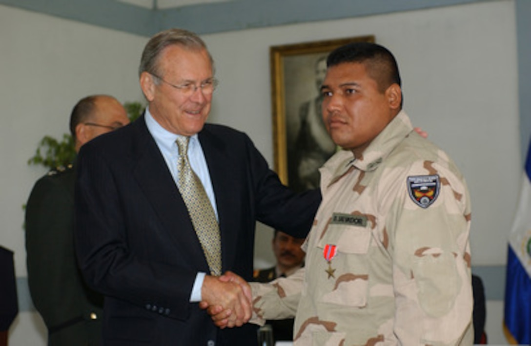 Secretary of Defense Donald H. Rumsfeld (left) congratulates an El Salvadoran soldier after awarding him the Bronze Star during an award ceremony at the El Salvadorian Military Academy on Nov. 12, 2004. Rumsfeld pinned the medal on six members of the Cuscatlan Battalion for heroism under fire in Iraq that saved the lives of six Coalition Provisional Authority workers. The troops, part of a 380-member Salvadoran contingent in Iraq conducting stability and support operations, were escorting a convoy of CPA workers when they were ambushed an insurgents armed with rocket-propelled grenades and automatic weapons. Rumsfeld earlier met with President Elias Antonio Saca and the Salvadoran Joint Chiefs of Staff to discuss issues affecting the two countries. 