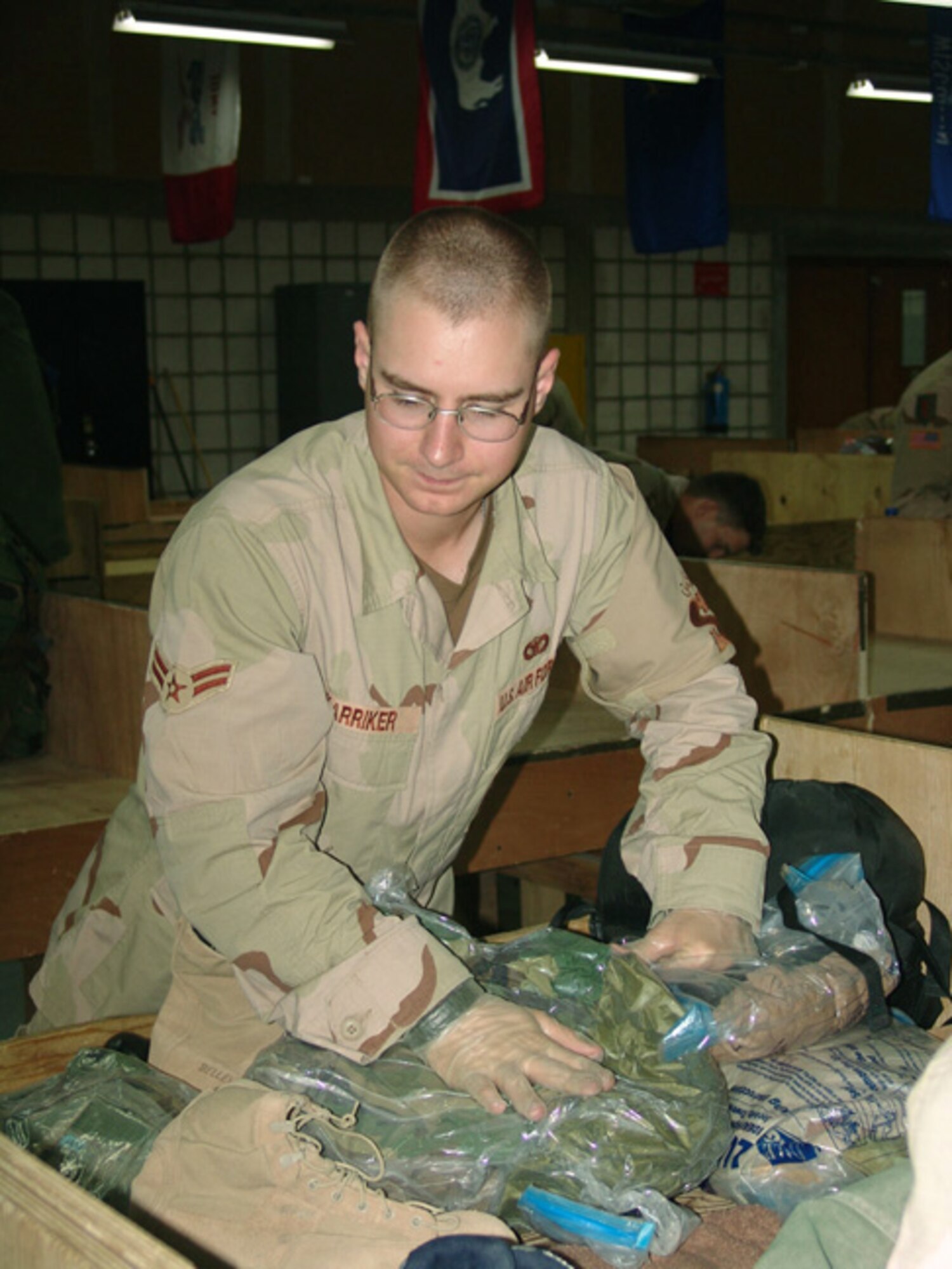 SOUTHWEST ASIA -- Airman 1st Class Joshua Karriker checks a Soldier's bag before clearing him through customs.  He and other 886th Expeditionary Security Forces Squadron customs inspectors check for prohibited items, such as agricultural products, war souvenirs and ammunition.  (U.S. Air Force photo by Capt. Aaron Burgstein)
