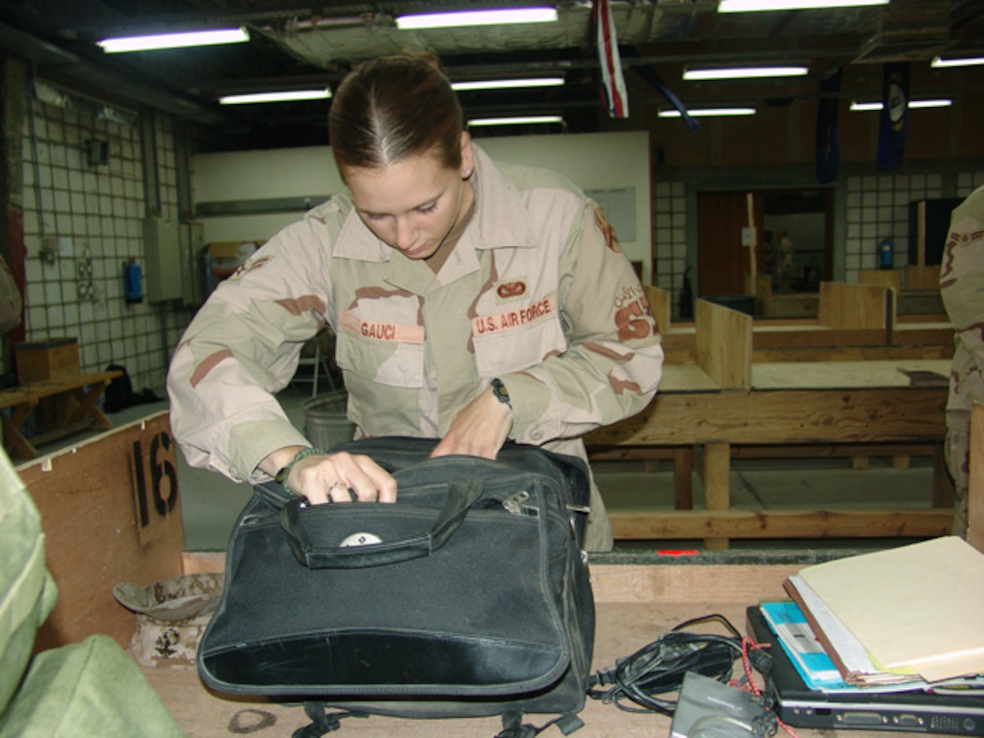 SOUTHWEST ASIA -- Airman 1st Class Emily Gauci checks a traveler's bag before clearing him through customs.  She and other 886th Expeditionary Security Forces Squadron customs inspectors are responsible for customs and agricultural inspections on people and vehicles returning to the United States.  (U.S. Air Force photo by Capt. Aaron Burgstein)
