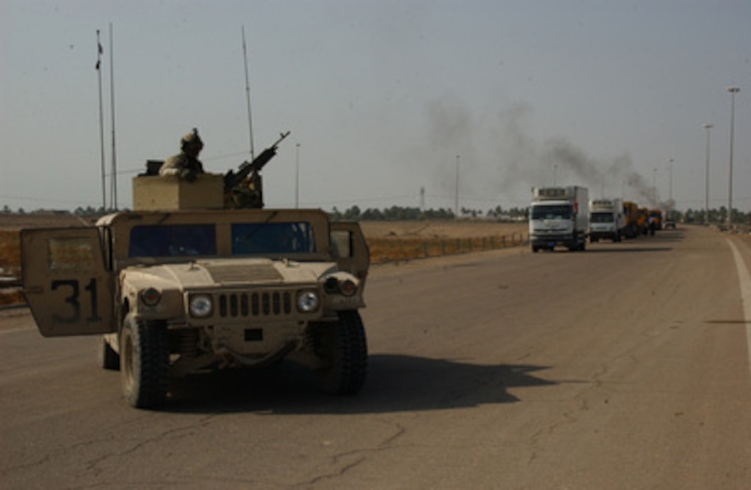 A Humvee pauses in the road as U.S. Marines and Army soldiers escort a 15-truck convoy of food and medicine supplies into Fallujah, Iraq, on Nov. 15, 2004. The Iraqi Minister of Trade arranged for the large shipment. The escort is being provided by soldiers in the 10th Mountain Division and Marines from the 1st Marine Division. 