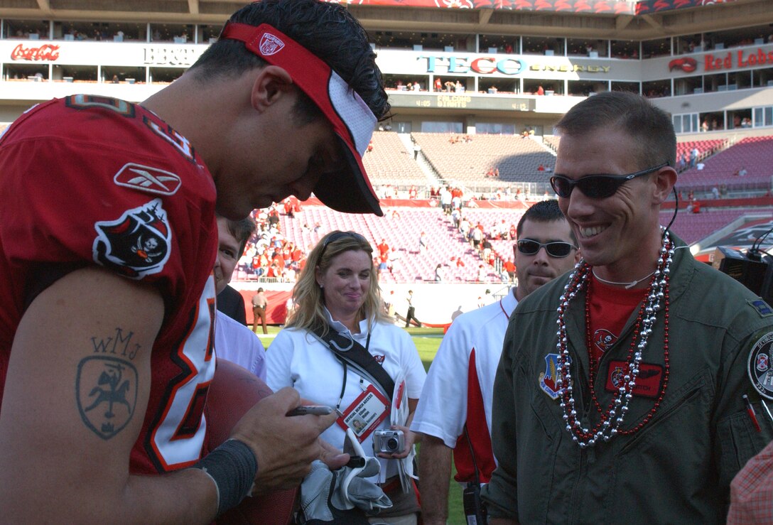 TAMPA, Fla. -- Tampa Bay Buccaneers wide receiver Joe Jurevicius autographs a game ball for Capt. Ryan Silver, a pilot from the 89th Flying Training Squadron at Sheppard Air Force Base, Texas.  Captain Silver was part of the ground control team that guided a flyover that his twin brother, Capt. Bryce Silver led over the stadium here during the opening ceremony.  The brother is assigned to the 333rd Fighter Squadron at Seymour Johnson AFB, N.C.  (U.S. Air Force photo by 1st Lt. Elizabeth Kreft) 