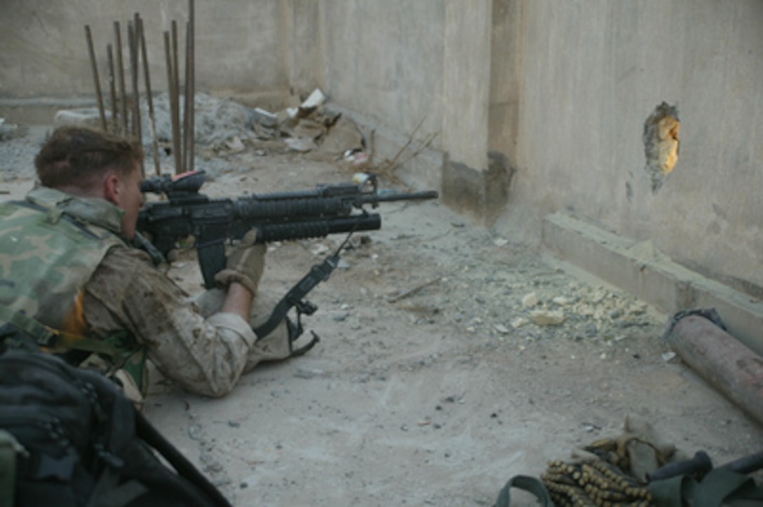A U.S. Marine watches through a hole in the wall insurgents running through the streets of Al Fallujah, Iraq, during Operation al Fajr (New Dawn) on Nov. 9, 2004. Al Fajr is an offensive operation to eradicate enemy forces within the city of Fallujah in support of continuing security and stabilization operations in the Al Anbar province of Iraq. 