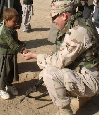 KHAROTI, Afghanistan -- A young villager shares the candy he just received with Staff Sgt. Michael McLaughlin, a 455th Expeditionary Civil Engineer Flight engineering assistant deployed from Dover Air Force Base, Del.  The Airman helped distribute clothes, shoes, toys and school supplies during a recent adopt-a-village visit.  (U.S. Air Force photo by Staff Sgt. Jennifer Lindsey)