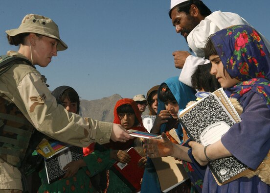 KHAROTI, Afghanistan -- Airman 1st Class Angelique Smith passes out coloring pencils and notebooks to young villagers during a recent adopt-a-village visit.  The 455th Expeditionary Support Squadron personnel support technician helped distribute toys and school supplies to more than 100 local children.  Airman Smith is deployed to nearby Bagram Air Base from Pope Air Force Base, N.C., supporting Operation Enduring Freedom.  (U.S. Air Force photo by Staff Sgt. Jennifer Lindsey)