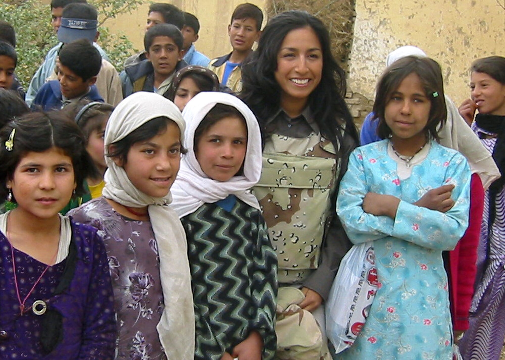CHARIKAR, Afghanistan -- Mili Suits stands with a group of Afghan children here.  She visited the village orphanage to help distribute $300 worth of shoes to the children residing in the youth shelter.  Funds for the footwear were donations raised through the 455th Air Expeditionary Wing's flag-flying program at nearby Bagram Air Base.  Ms. Suits is an airfield manager participating in the Air Force Contract Augmentation Program.  (U.S. Air Force photo by 2nd Lt. Michael Sheley)