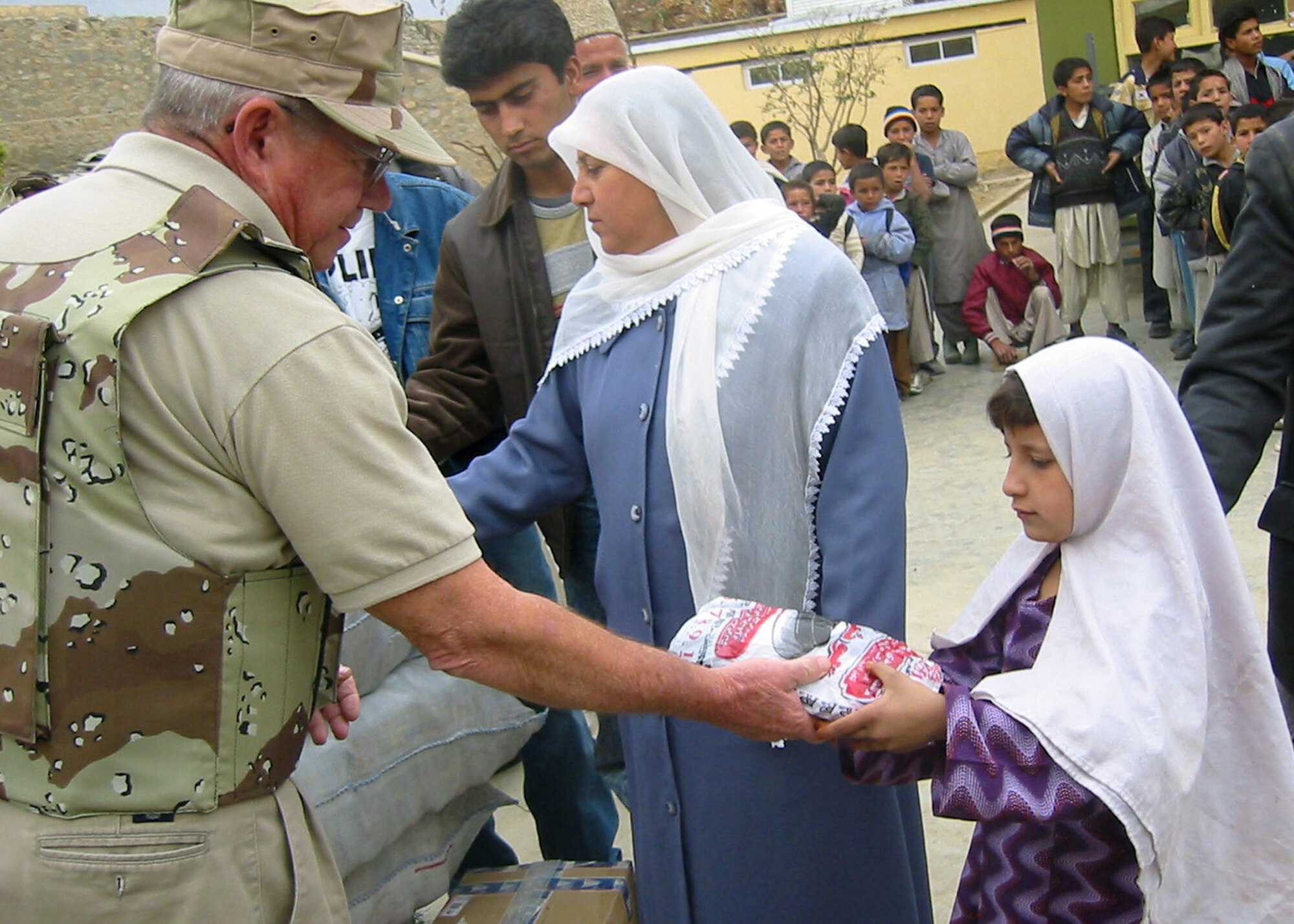 CHARIKAR, Afghanistan -- Barry McKelvy hands a bag of winter shoes to an Afghan child.  He visited the village orphanage to help distribute $300 worth of shoes to the children residing in the youth shelter.  Funds for the footwear were donations raised through the 455th Air Expeditionary Wing's flag-flying program at nearby Bagram Air Base.  Mr. McKelvy is the coordinator of the program.  He is also an airfield manager participating in the Air Force Contract Augmentation Program.  (U.S. Air Force photo by 2nd Lt. Michael Sheley)