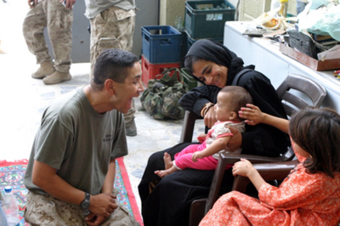 U.S. Marine Staff Sgt. W.P. Ybarra plays with a young Iraqi while his fellow Marines provide food and water to the family during a patrol in Fallujah, Iraq, on Nov. 16, 2004. The Marines are patrolling Fallujah as part of Operation al Fajr (New Dawn). Ybarra is assigned to India Company, 3rd Battalion, 5th Marine Regiment, Fleet Marine Force. 
